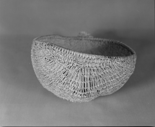 Private Collection. Object: Miwok basket. Dimensions: 9 1/2 x 4 1/2 x 8". Materials: Scraped shoots, split shoots, bracken fern root, and cotton string. Technology: Diagonally twined, up to right slant of turns, alternate rows with alternate slant. 1/3 of way from start of basket end selvage warp rods bent & lashed with additional bundle of rods coiled on top to even out rim contour. Rimstick attached with the aid of an awl lapping on one side. Repair in commericial cotton cordage apparently using a needle which secures short sections of willow sticks much in the manner of Anglo sock darning. Collection History: Purchased at 3 Flags Trading Post, Coleville, CA. with Miwok identification. Catalogued by Craig Bates and Barbara Beroza. Yosemite Collections, National Park Service.