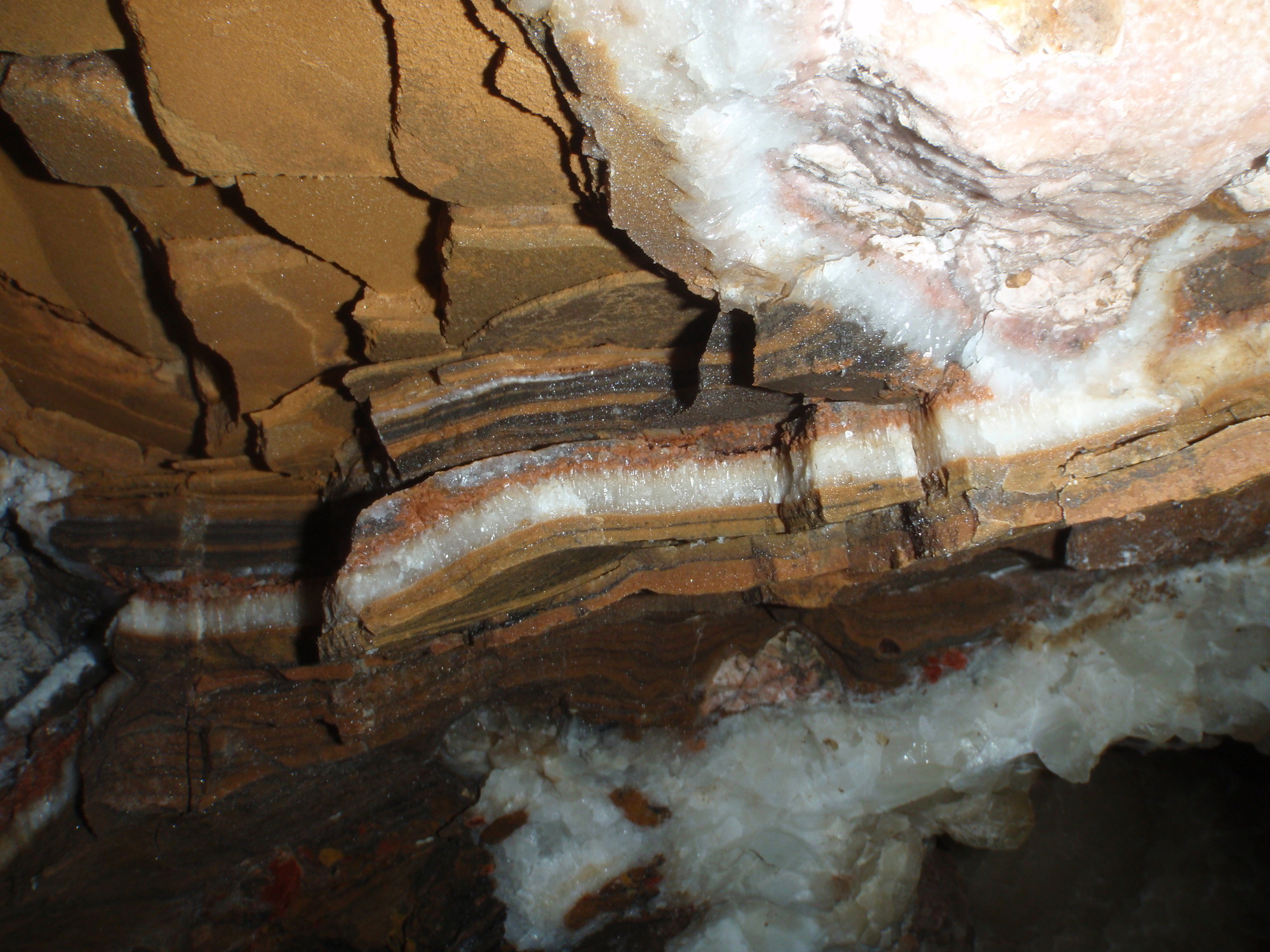 White, red and brown layers of rock including calcite and manganese
