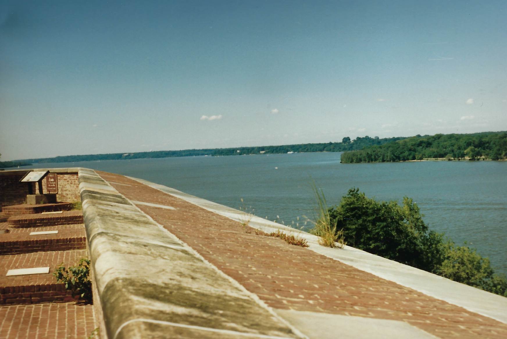 Photo of the top of the parapet wall, with cannon mounts to the left and the Potomac River to the right showing the Virginia shoreline