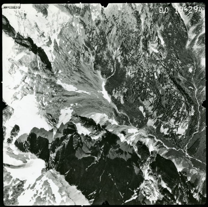 Black and white aerial photograph of glaciated mountain peaks and valleys.