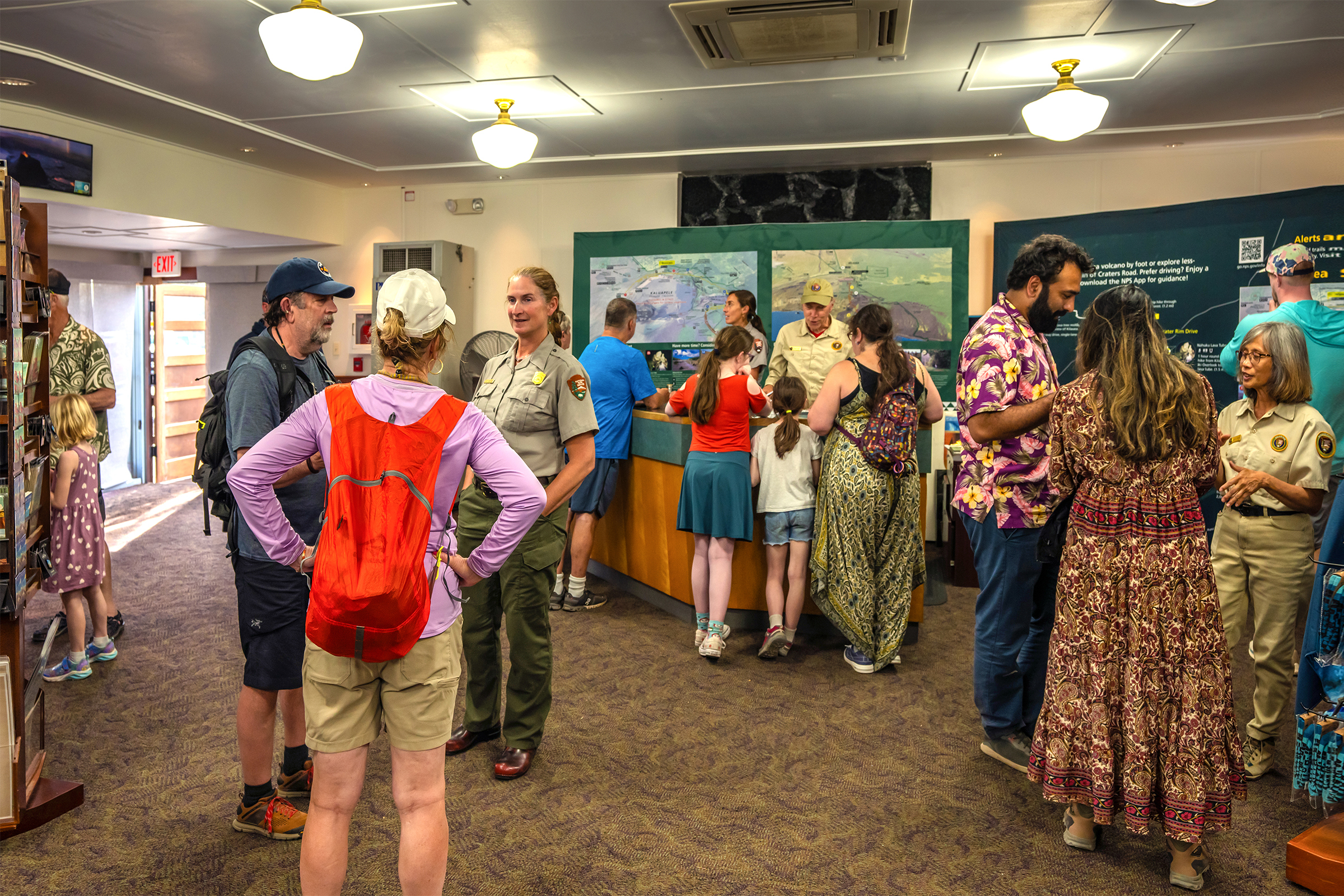 Visitors standing in a welcome center are assisted by park staff and volunteers 