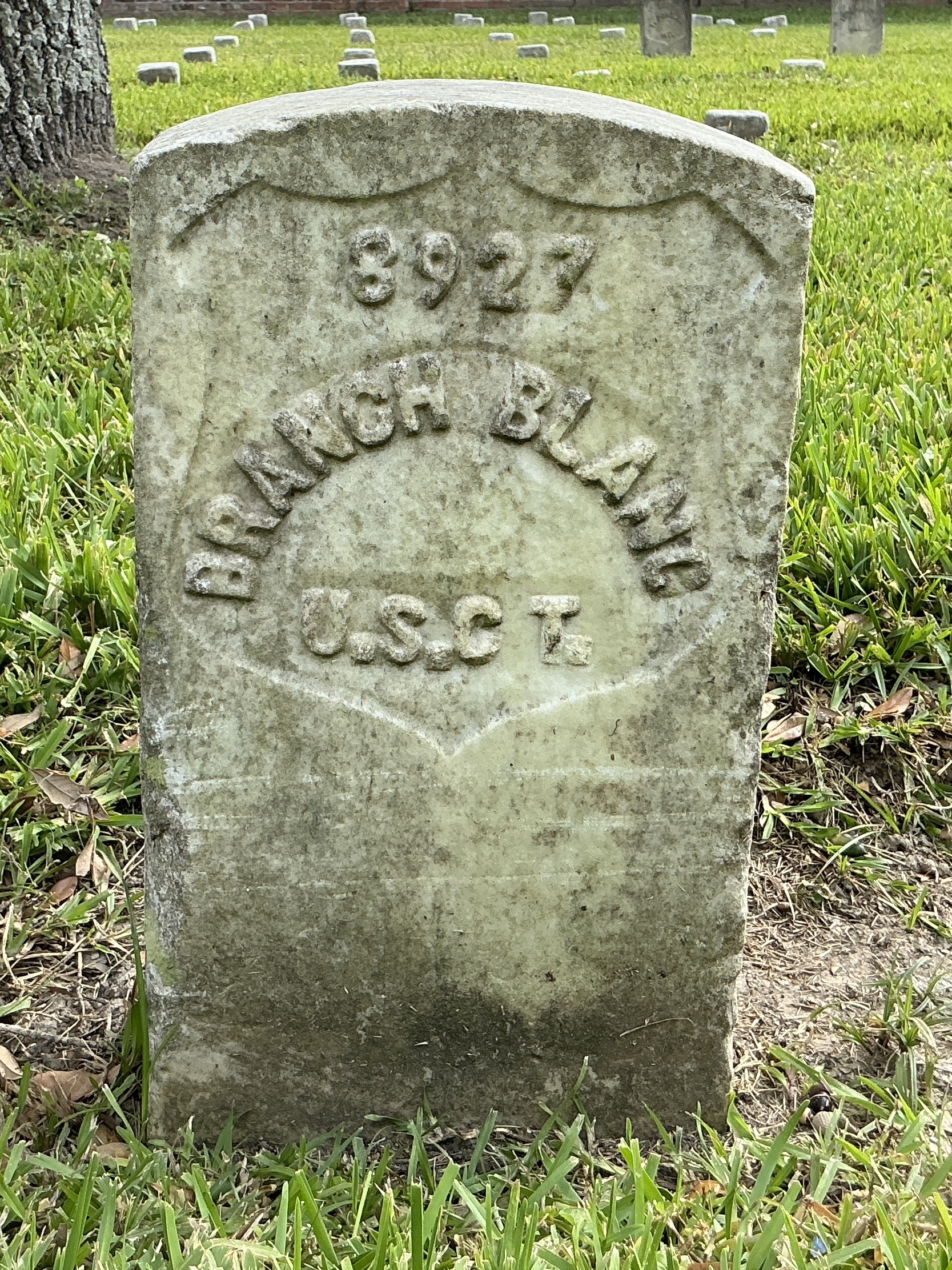 Front of historic upright marble headstone with recessed shield with recessed lettering face.