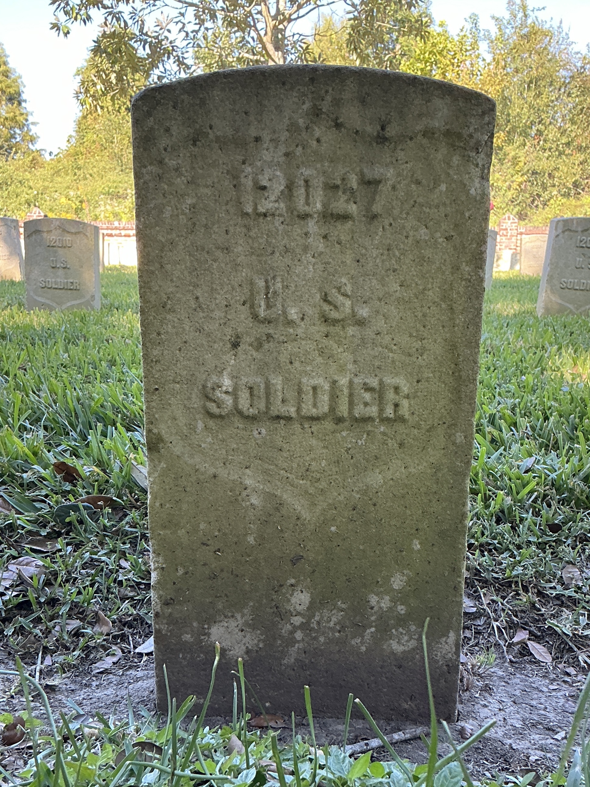 Front of historic upright marble headstone with recessed shield face.