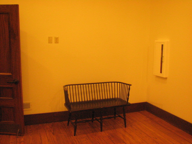 Black bench with spindle back and arm rests, seats two people.