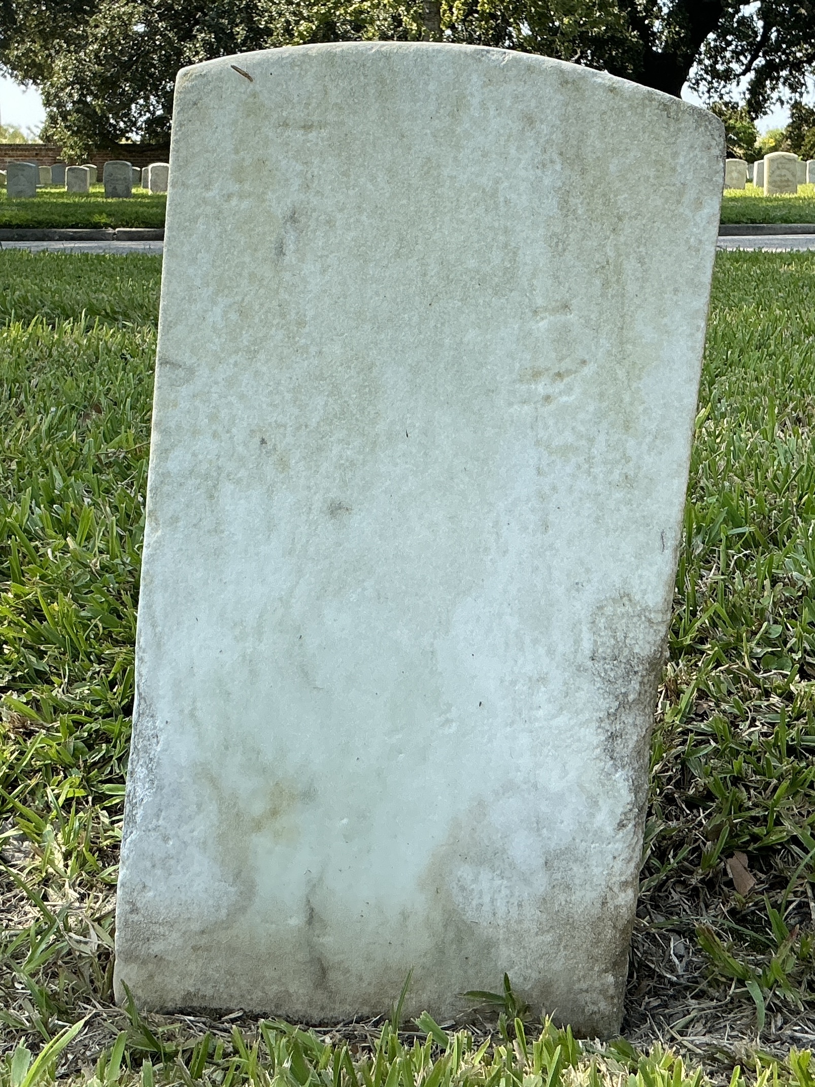 Back of historic upright marble headstone with recessed shield face.