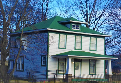 The Clinton Birthplace Home is a two-story structure in American Foursquare design. The exterior features white paneling with green trim around each outside window as well as a green shingled roof and porch. 