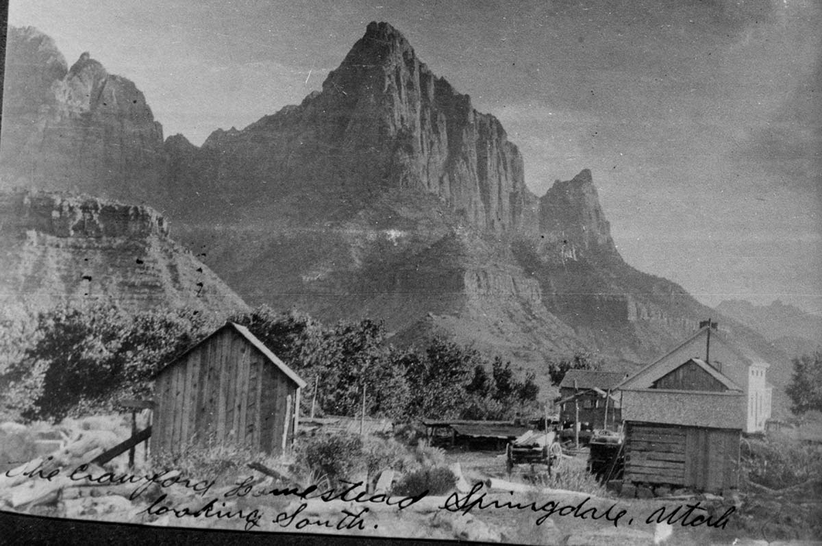 Crawford homestead, circa 1900. View looking south, Watchman Peak in the background. Photo by William Crawford. Low object between the buildings and behind the wagon is 'fruit drying scaffold' where fruit was dried to preserve it for winter.
