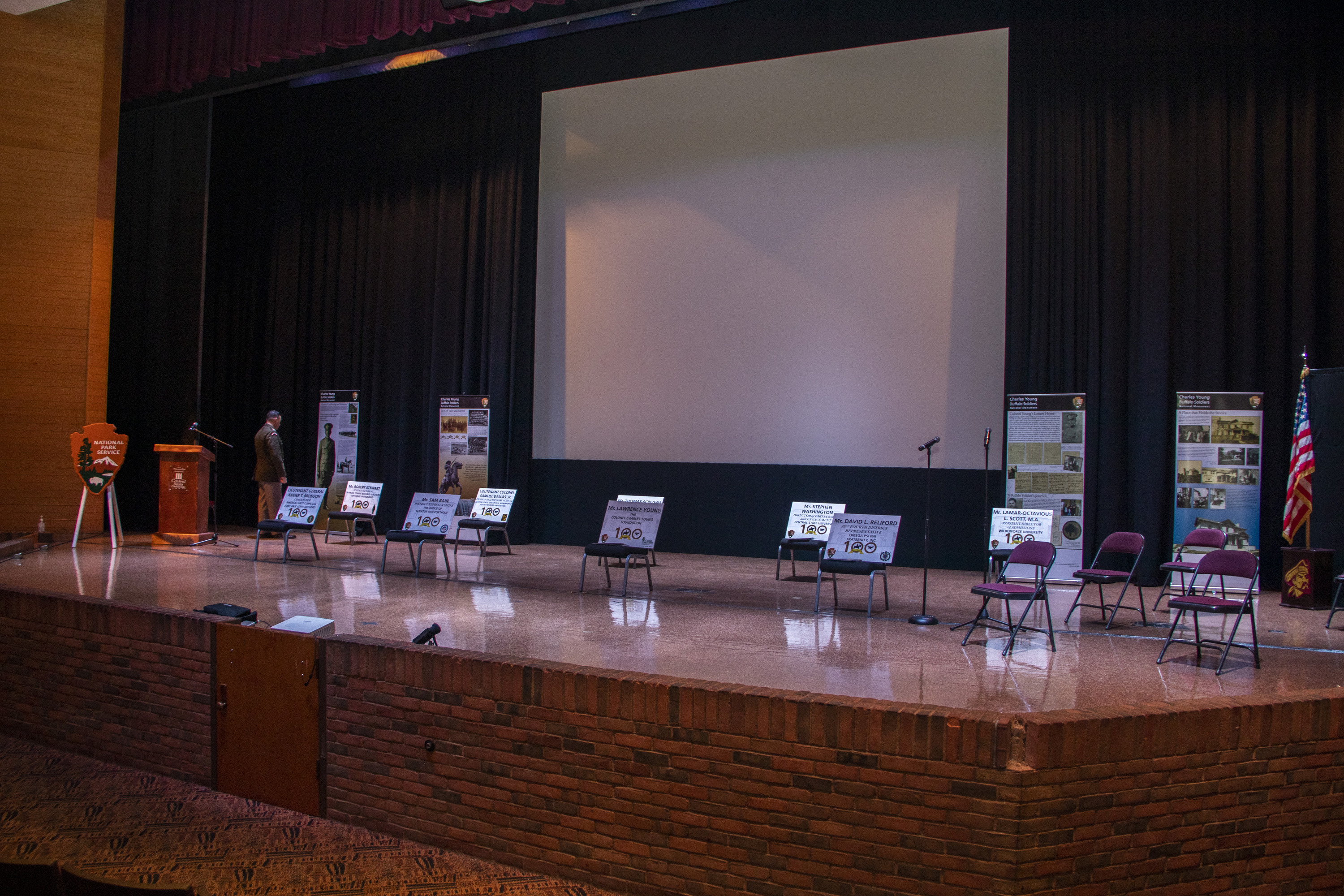 Empty chairs on a stage with large white screen in the background