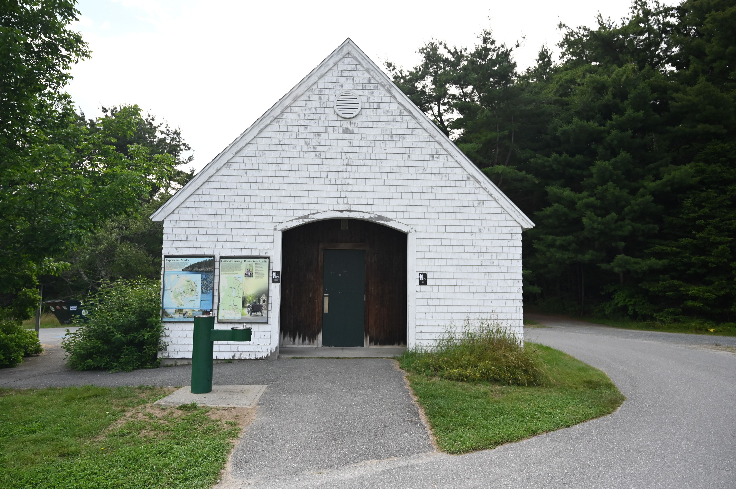 Large white building with triangular pointed roof and a water station infront to the left. 