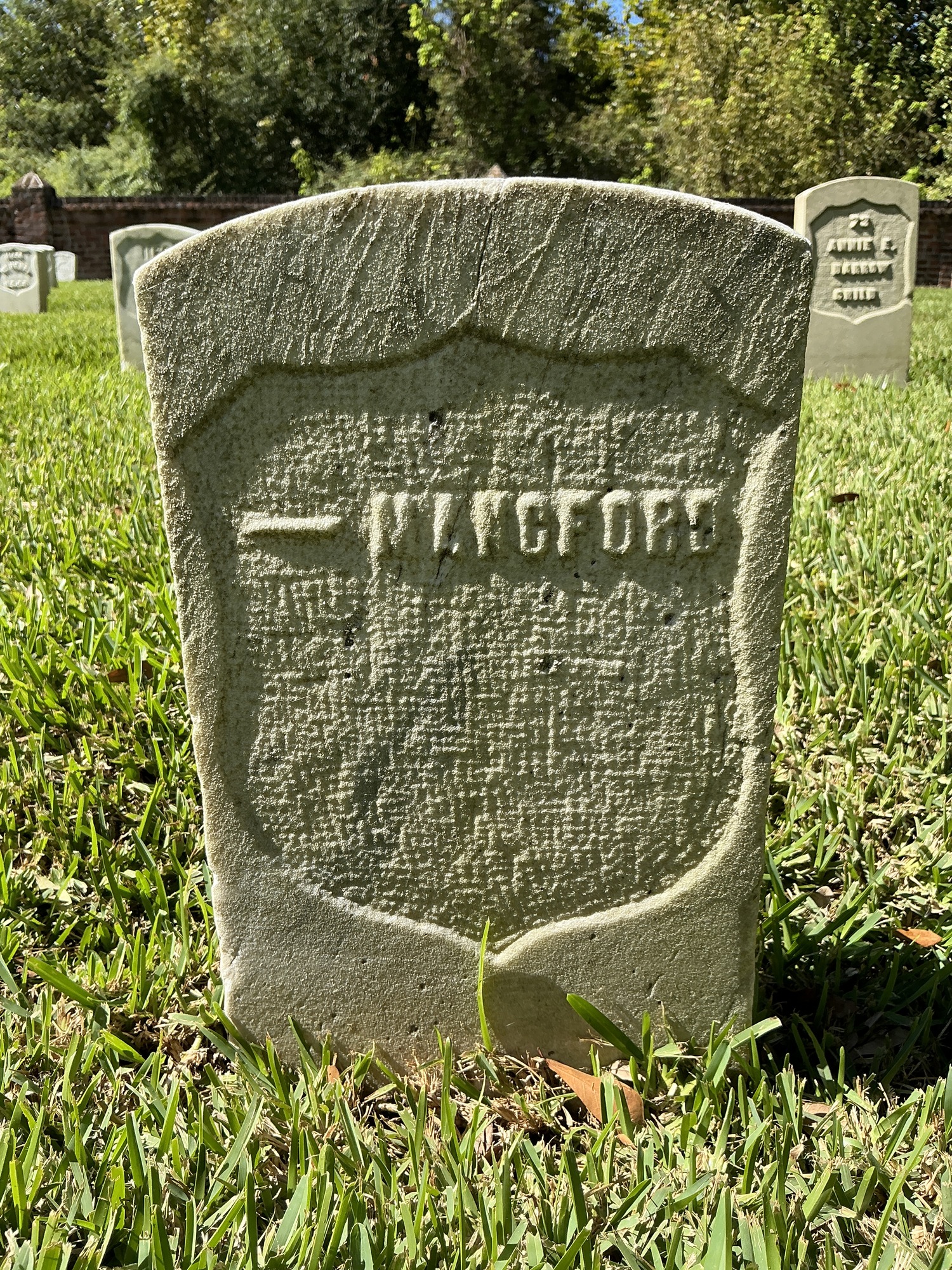 Front of historic upright marble headstone with recessed shield face.
