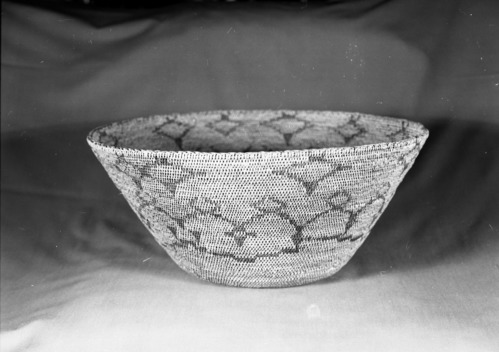 Private Collection. Object: Miwok basket. Dimensions: 17 1/2 x 17 1/2". Materials: Bull pine branchlets and redbud. Technology: Single rod, clockspring start, overstitched start, interlocking stitch, fag ends trimmed on work face, moving ends trimmed on interior. Herringbone rim finish splitting top rod. Collection History: Made by Matilda, a Sonora Miwok. Photographed by Michael Dixon. Catalogued by Craig Bates and Barbara Beroza. Yosemite Collections, National Park Service.