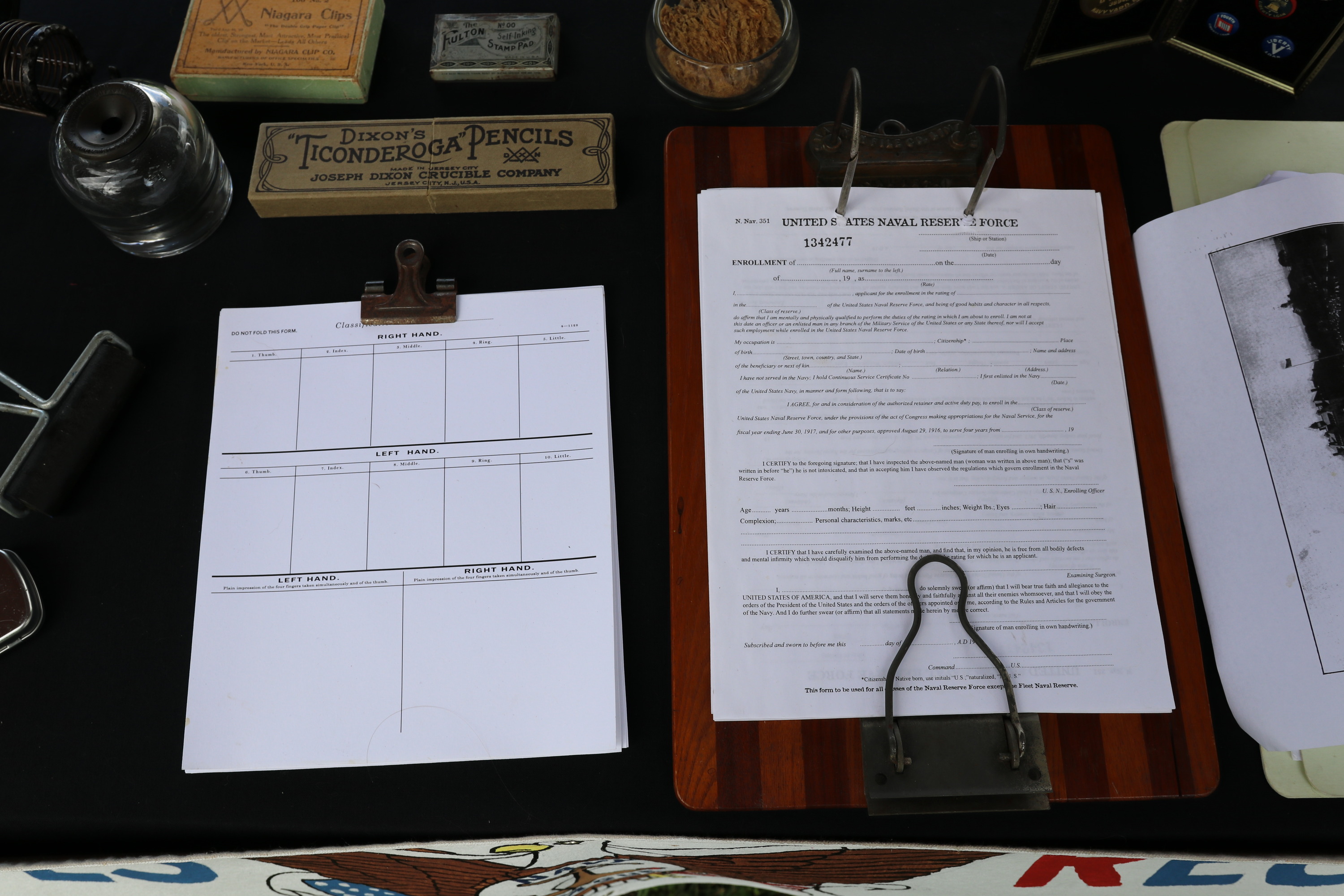 Several clerical paper reproductions sit on a table with a dark tablecloth. 