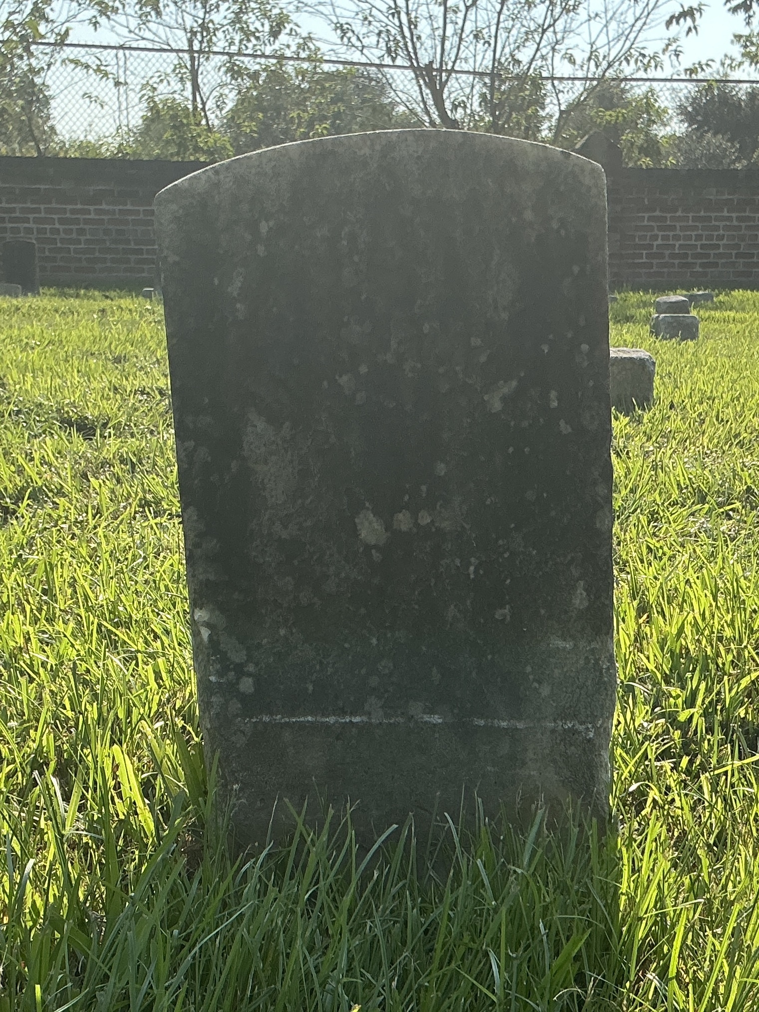 Front of historic upright marble headstone with recessed shield face.