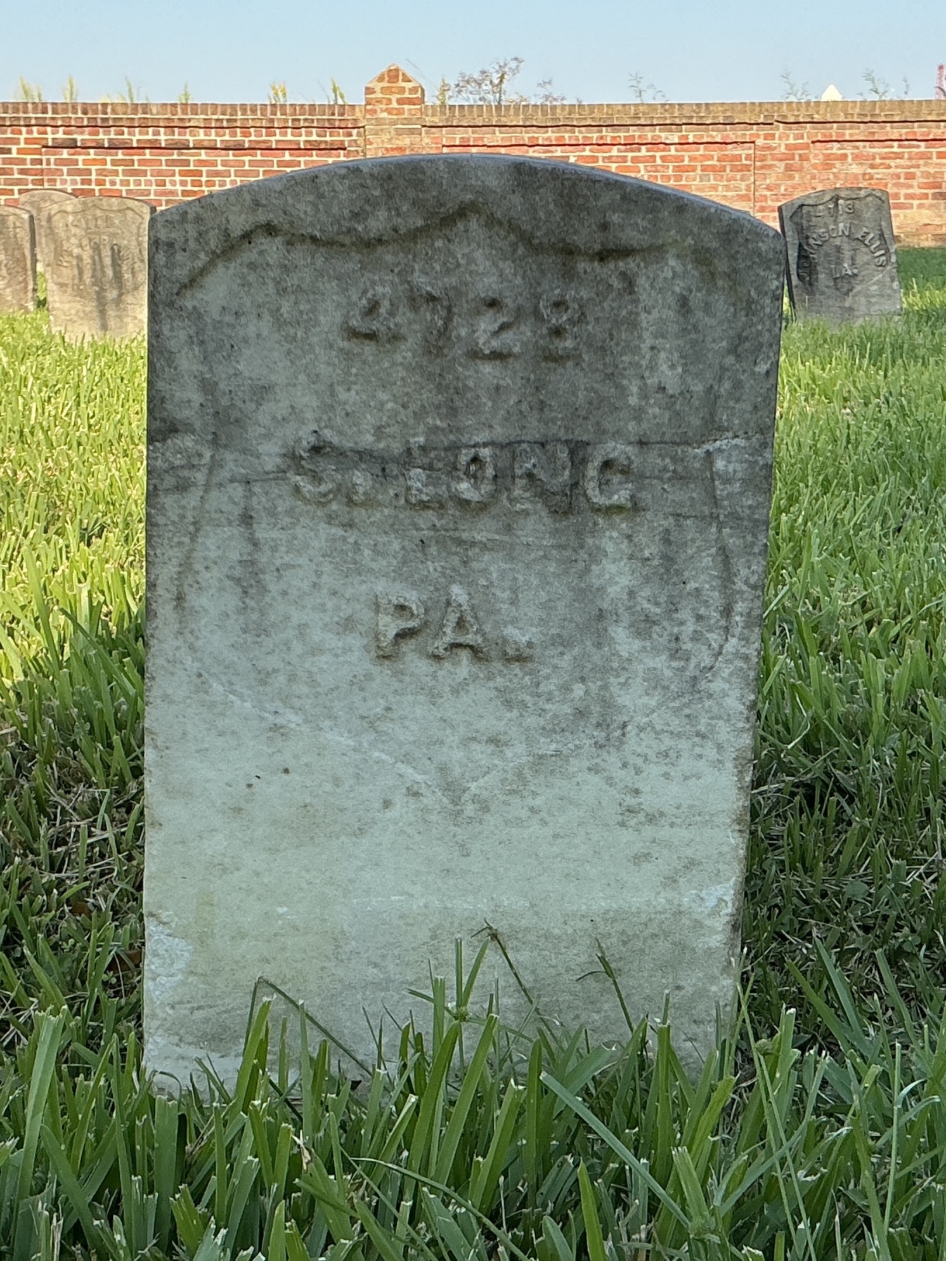 Front of historic upright marble headstone with recessed shield face.