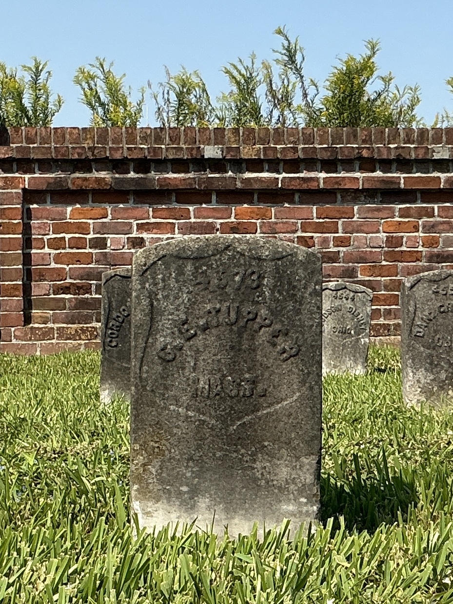 Front of historic upright marble headstone with recessed shield face.