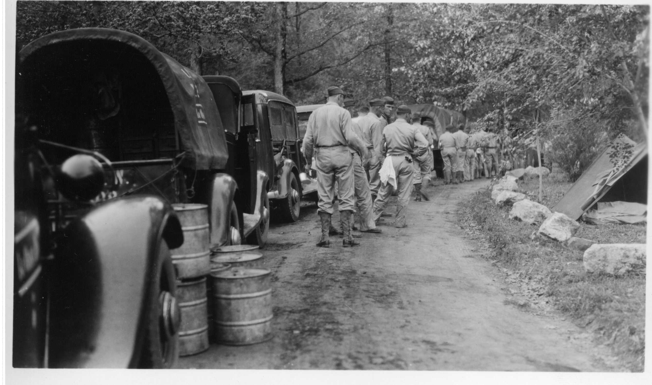 Company of soldiers camped at Gulpha Gorge; pup tent pitched on left; many men in army shirts lined up beside covered trucks. Typed description on back 1st. Observation Battalion, Fort Bragg, N.C. Gulpha Gorge Camp Ground. April 26, 1939.