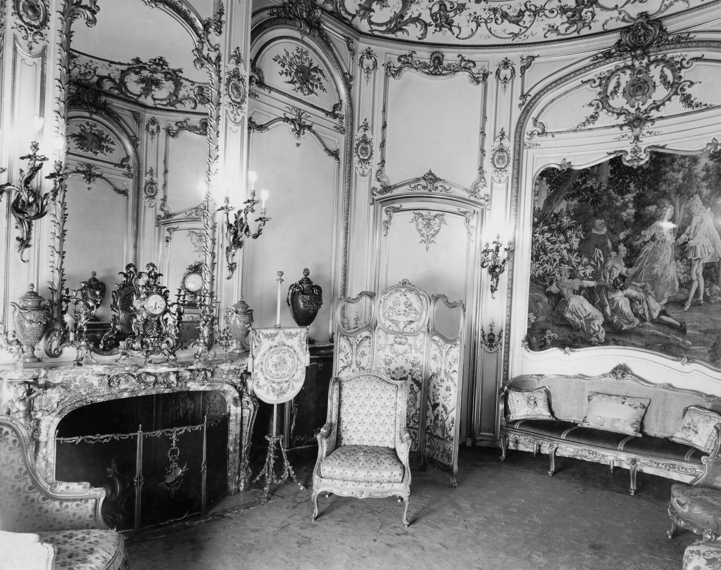 A small room with gilded furniture, ornately decorated walls, and a large marble fireplace.