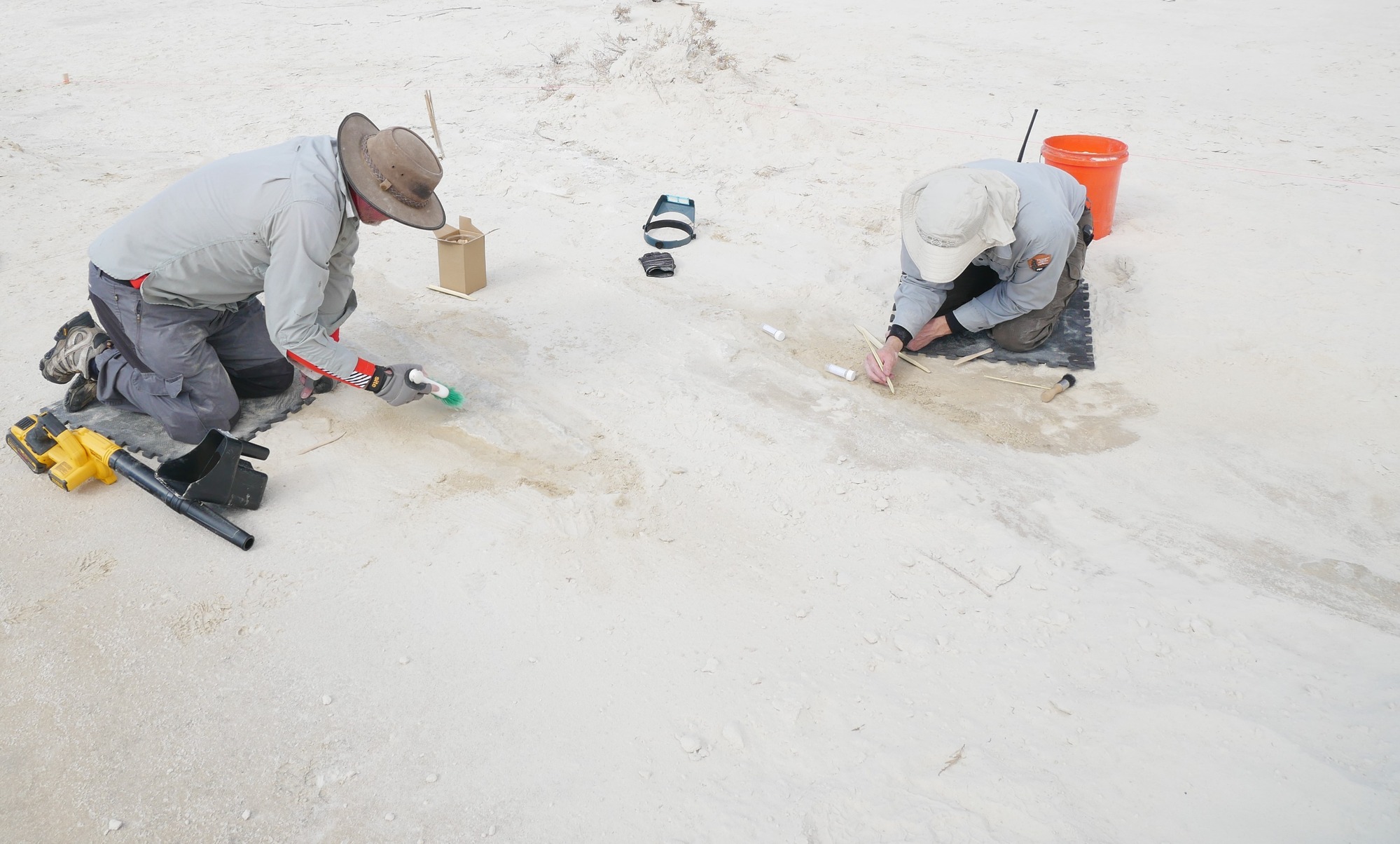 Two researchers using two different methods to uncover footprints.
