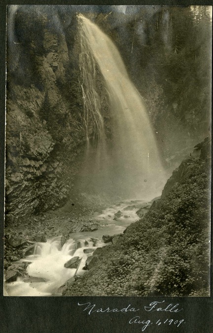 Historic photo of a large waterfall dropping off lava cliffs into a narrow river canyon. Text written below the photo reads "Narada Falls, Aug 1, 1909."