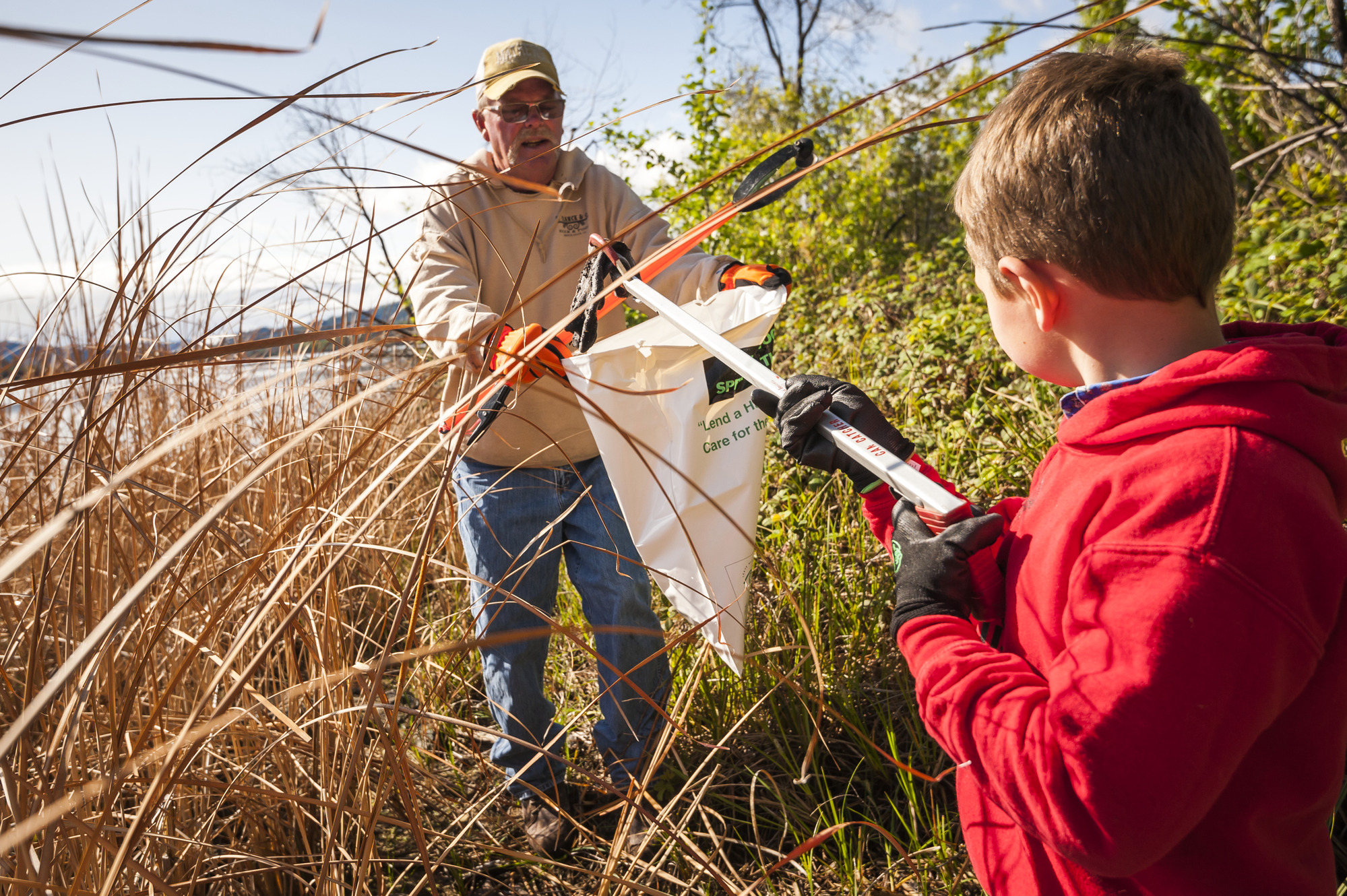 Two volunteers bagging trash along the lakeshore.