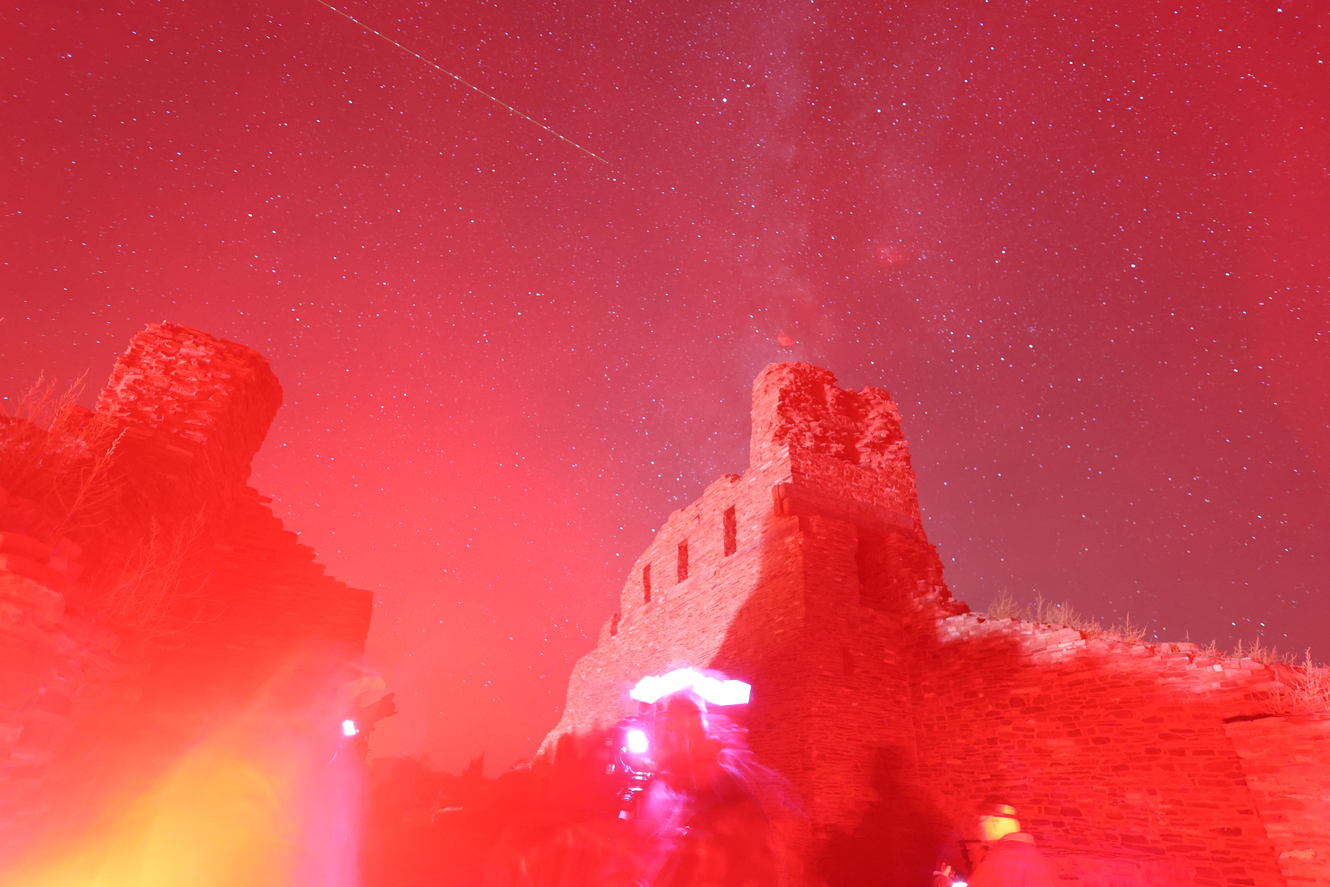 Milky Way in a starry sky with red sandstone church remnants in the foreground with a red glow.