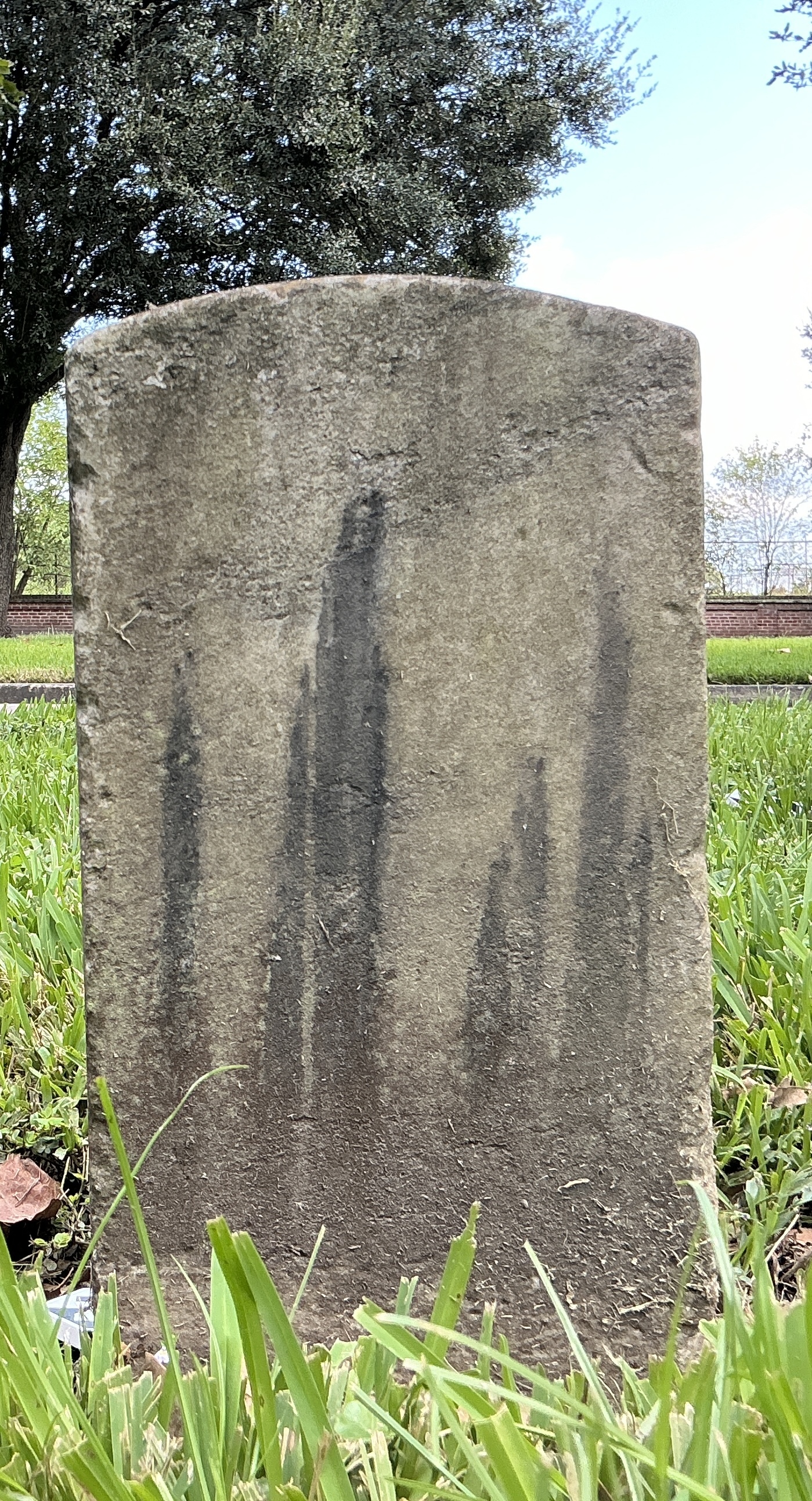 Back of historic upright marble headstone with recessed shield face.