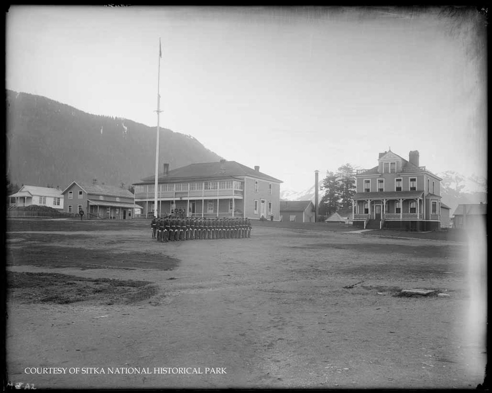 A squad of Marines in dress uniform standing at attention on the parade ground. 