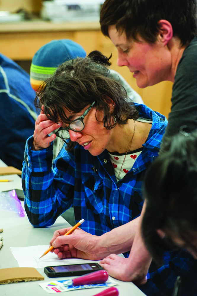 Woman with pencil sketches on paper with an activity participant