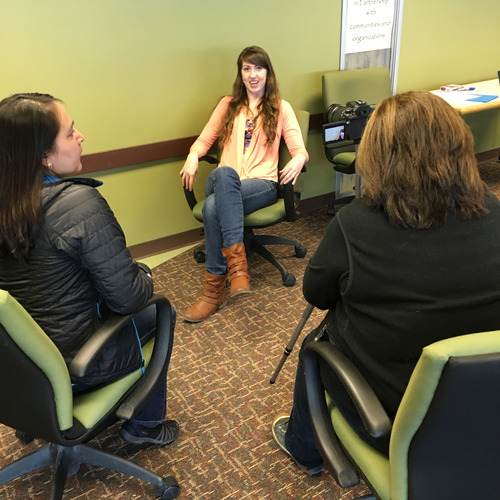 Three students practice video recording interviews with each other.