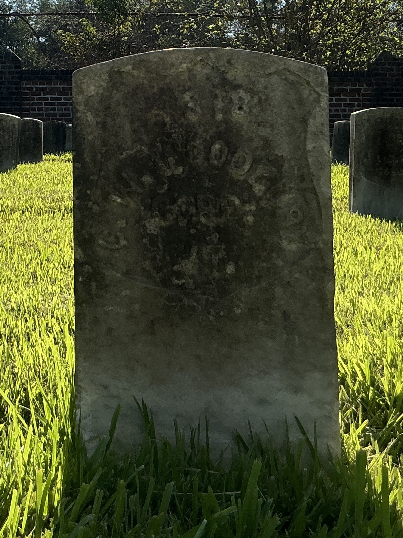 Front of historic upright marble headstone with recessed shield face.