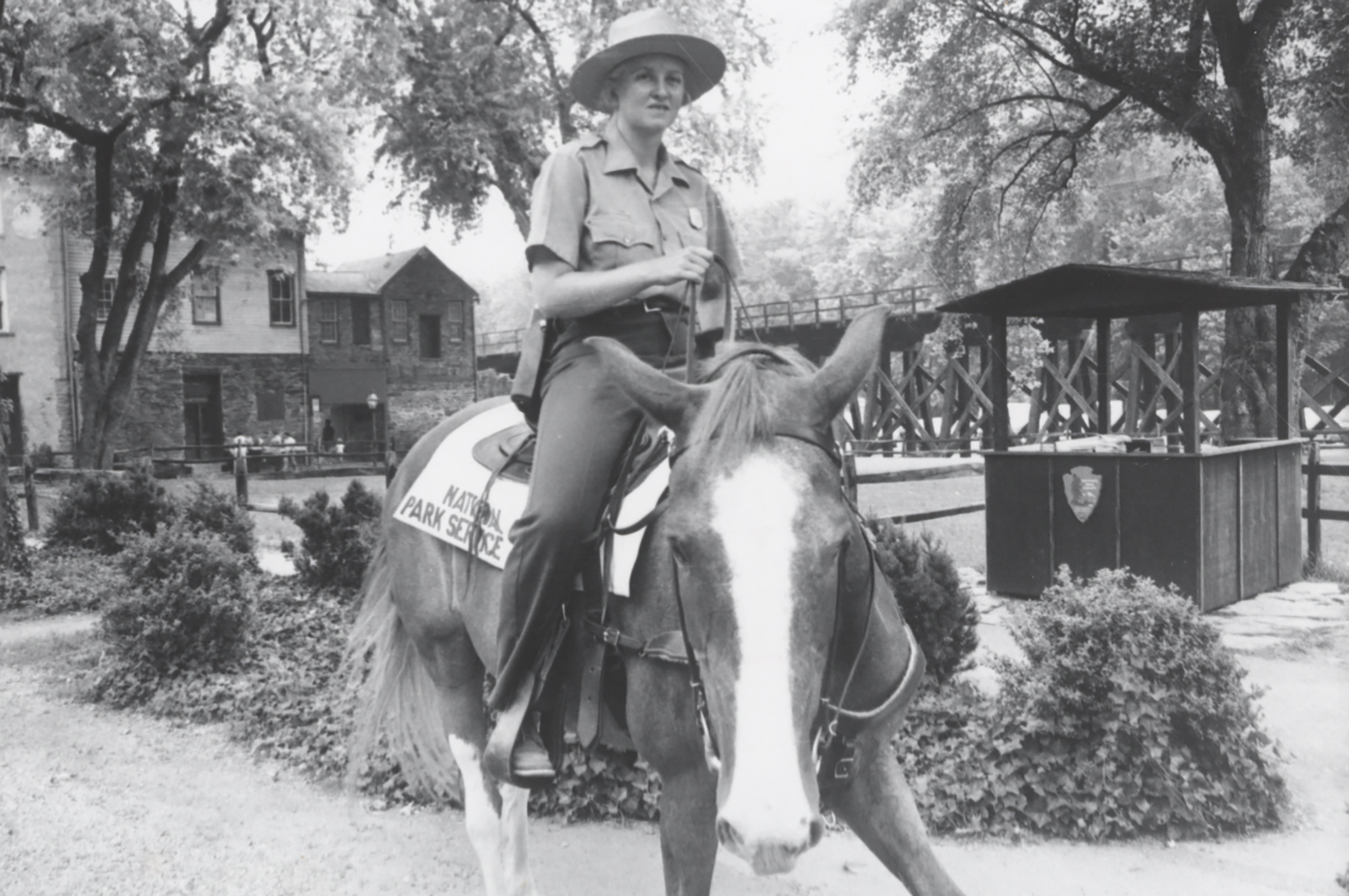 Christy Harris in her NSP uniform with broad-brimmed hat rides astride a horse. 