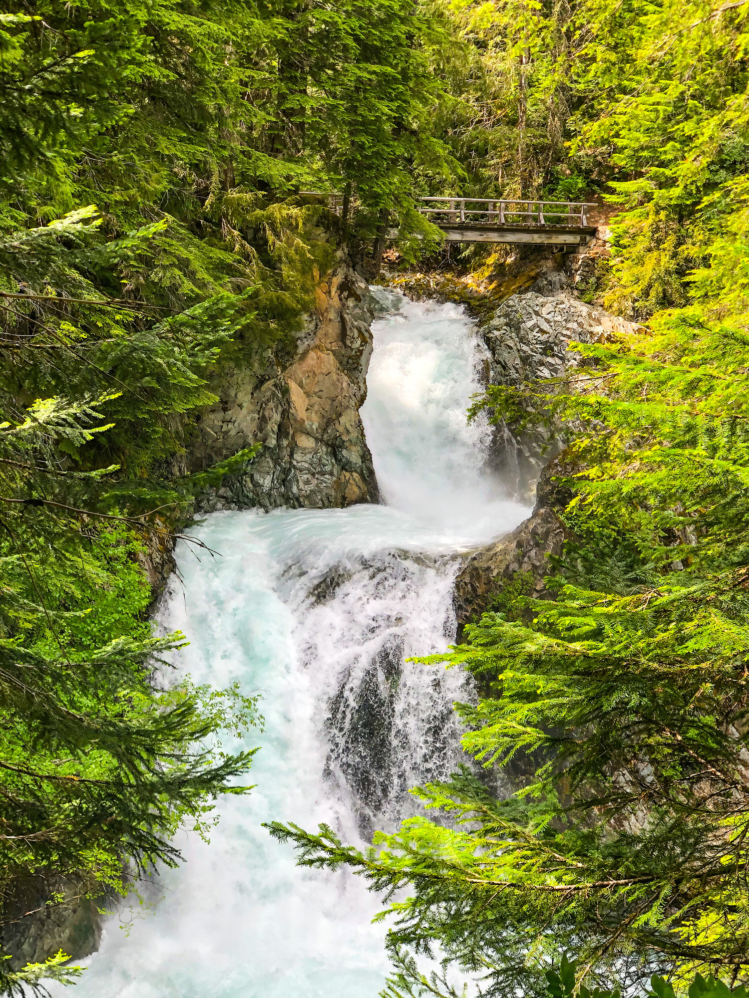 Water cascades, under a bridge and down a rocky ledge. 