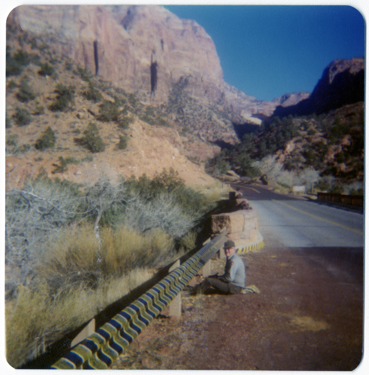Man painting stripes on road side barrier.
