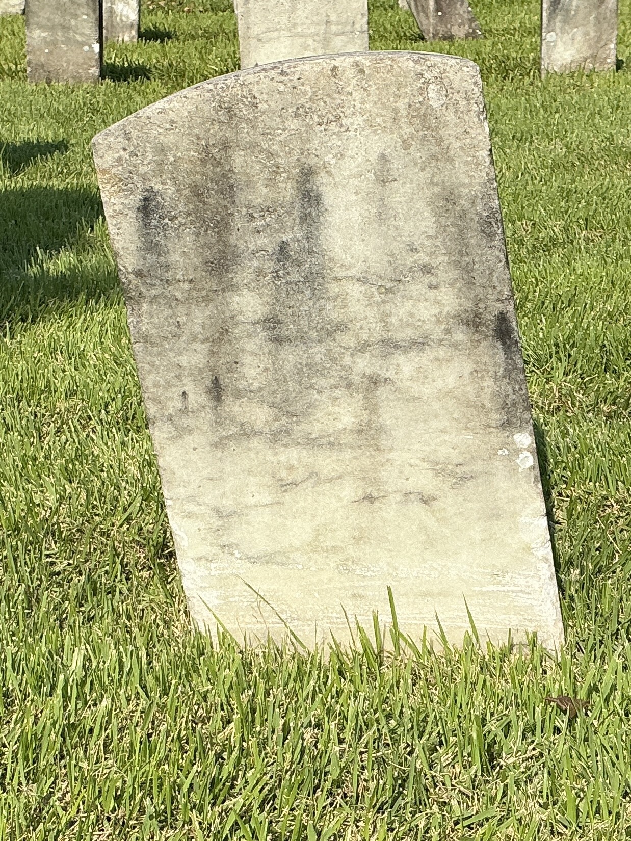 Back of historic upright marble headstone with recessed shield face.