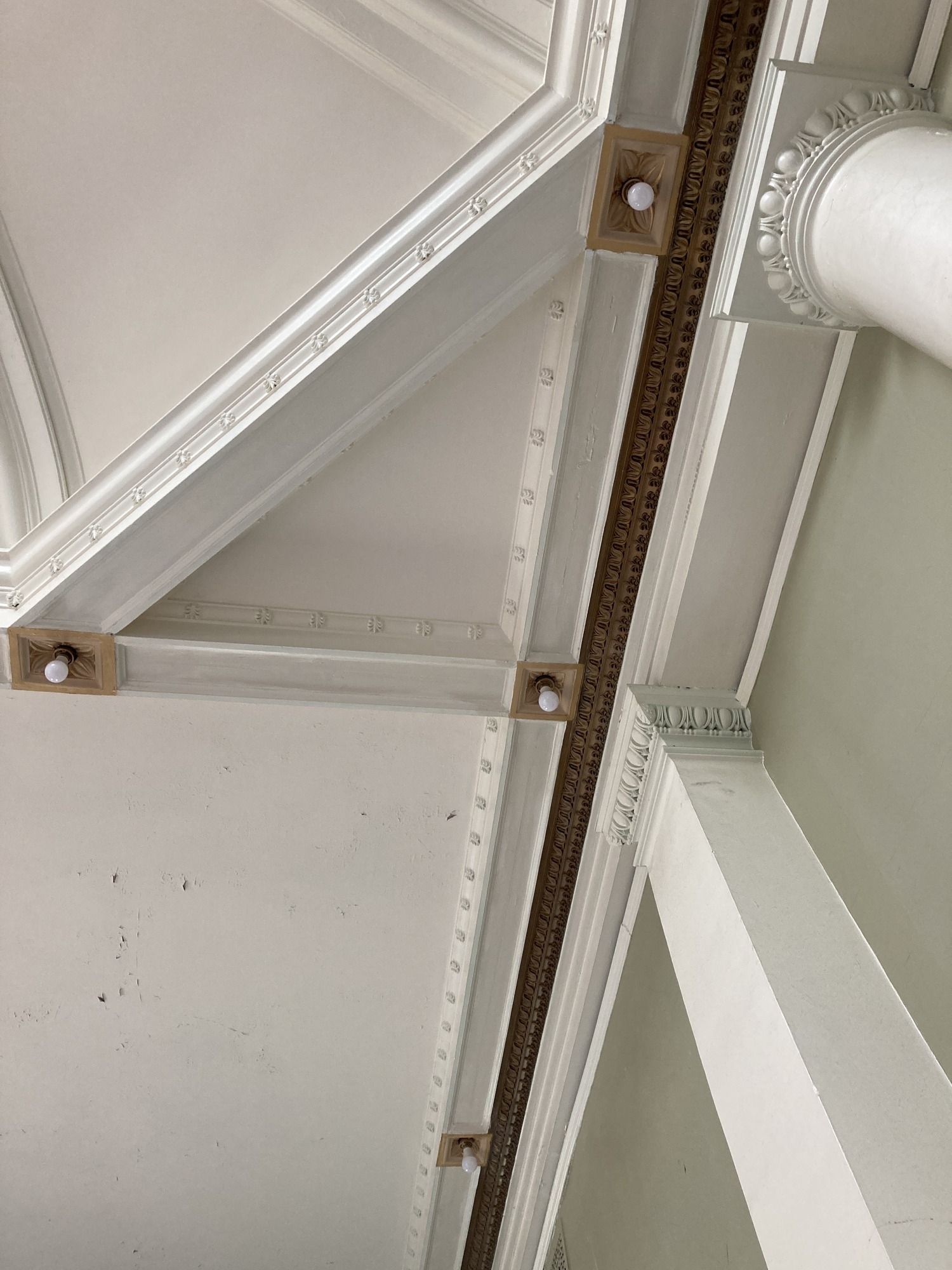 Ceiling with molding and three lightbulbs recessed in decorative medallions. 