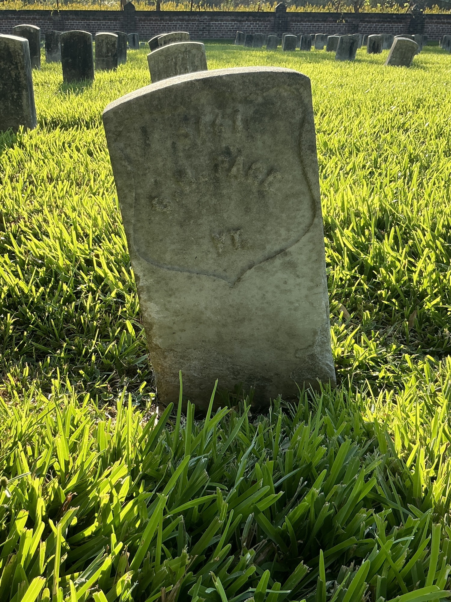 Front of historic upright marble headstone with recessed shield face.