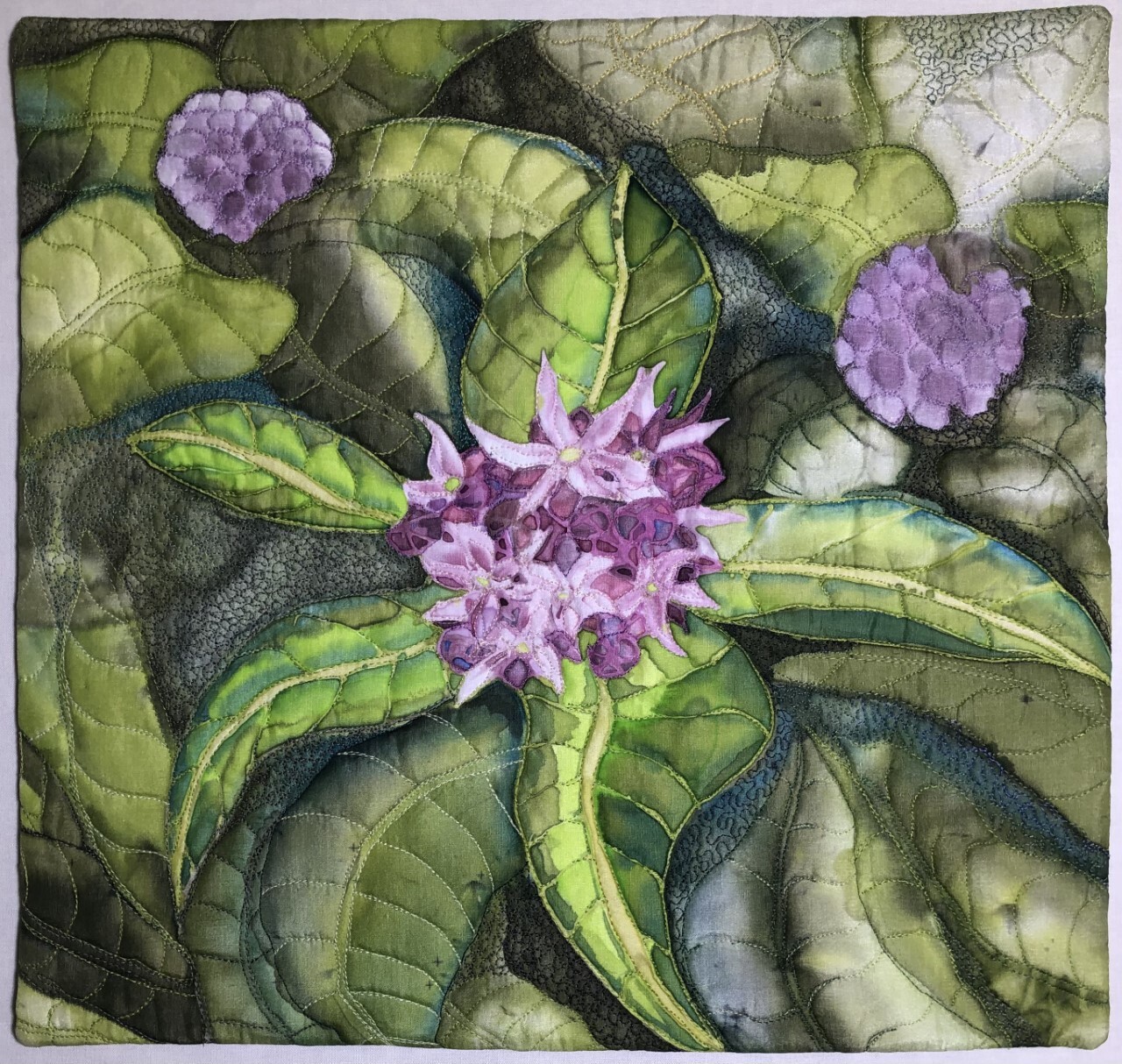 Quilted and painted fabric creates an image of a cluster of purple flowers surrounded by long, pointed green leaves.