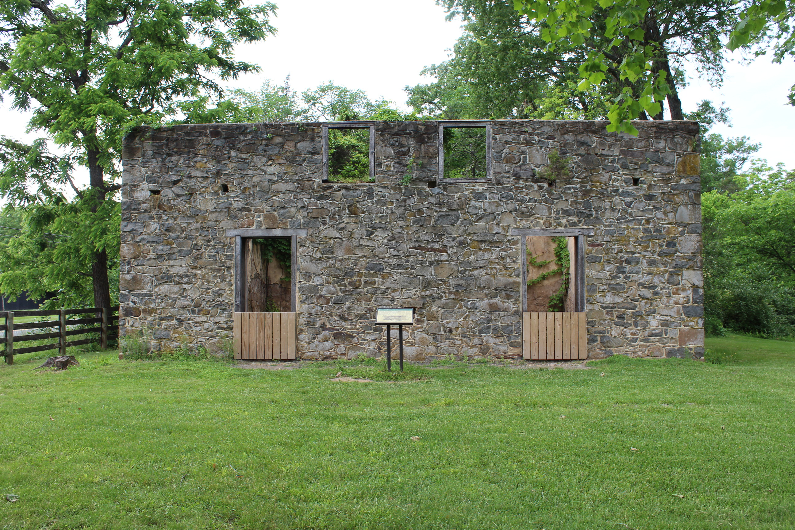 Historic brick building with a door on each side and an information sign in front