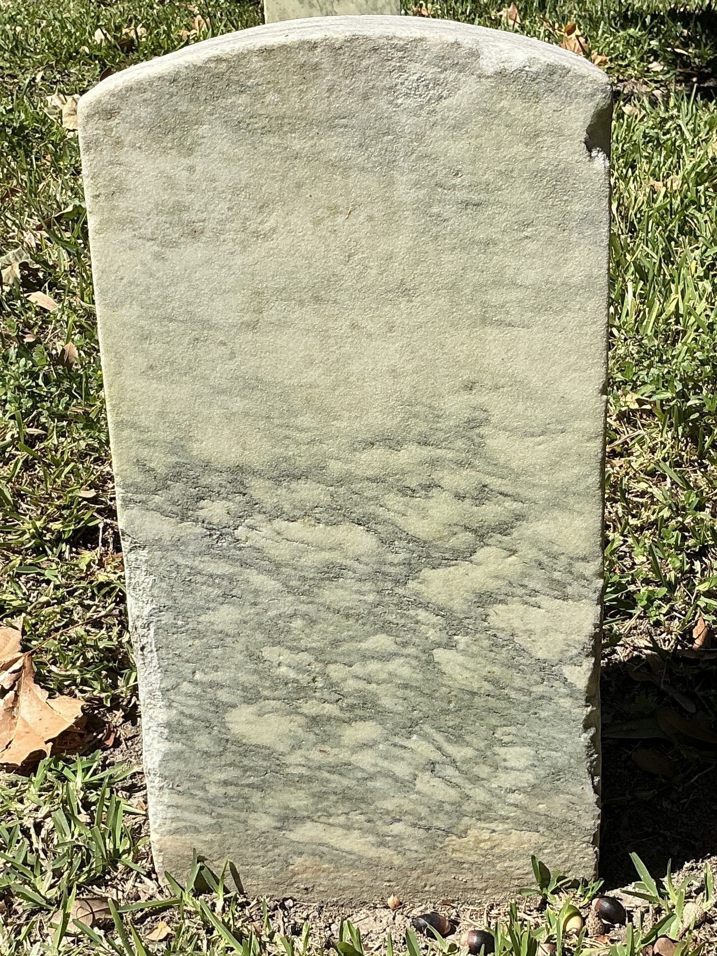 Back of historic upright marble headstone with recessed shield face.