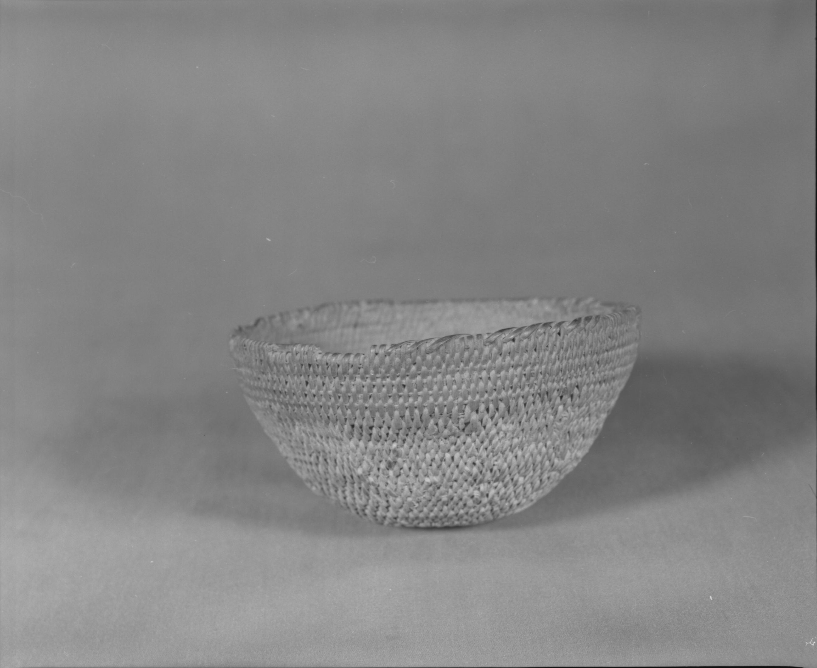 Private Collection. Object: Miwok basket. Dimensions: 5 1/2 x 2 1/2". Materials: Split shoot on lower two-thirds, different split shoot on upper third of basket. Technology: Single rod construction, lower 2/3 fag ends are tucked under previous stitch, moving ends appear to be tucked and trimmed off on the interior; last 1/3 of basket made by splitting foundation rod, overstitching on rim three times around. Collection History: Purchased from Maggie Longfellow's mother, also known as Mrs. Longfellow Poncho. Photographed by Michael Dixon. Catalogued by Craig Bates and Barbara Beroza. Yosemite Collections, National Park Service.