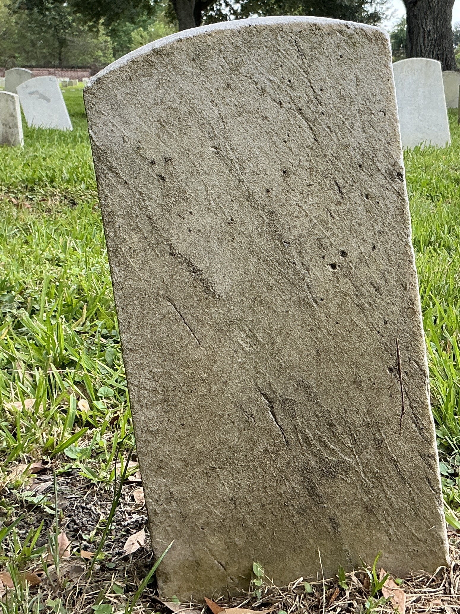 Back of historic upright marble headstone with recessed shield face.