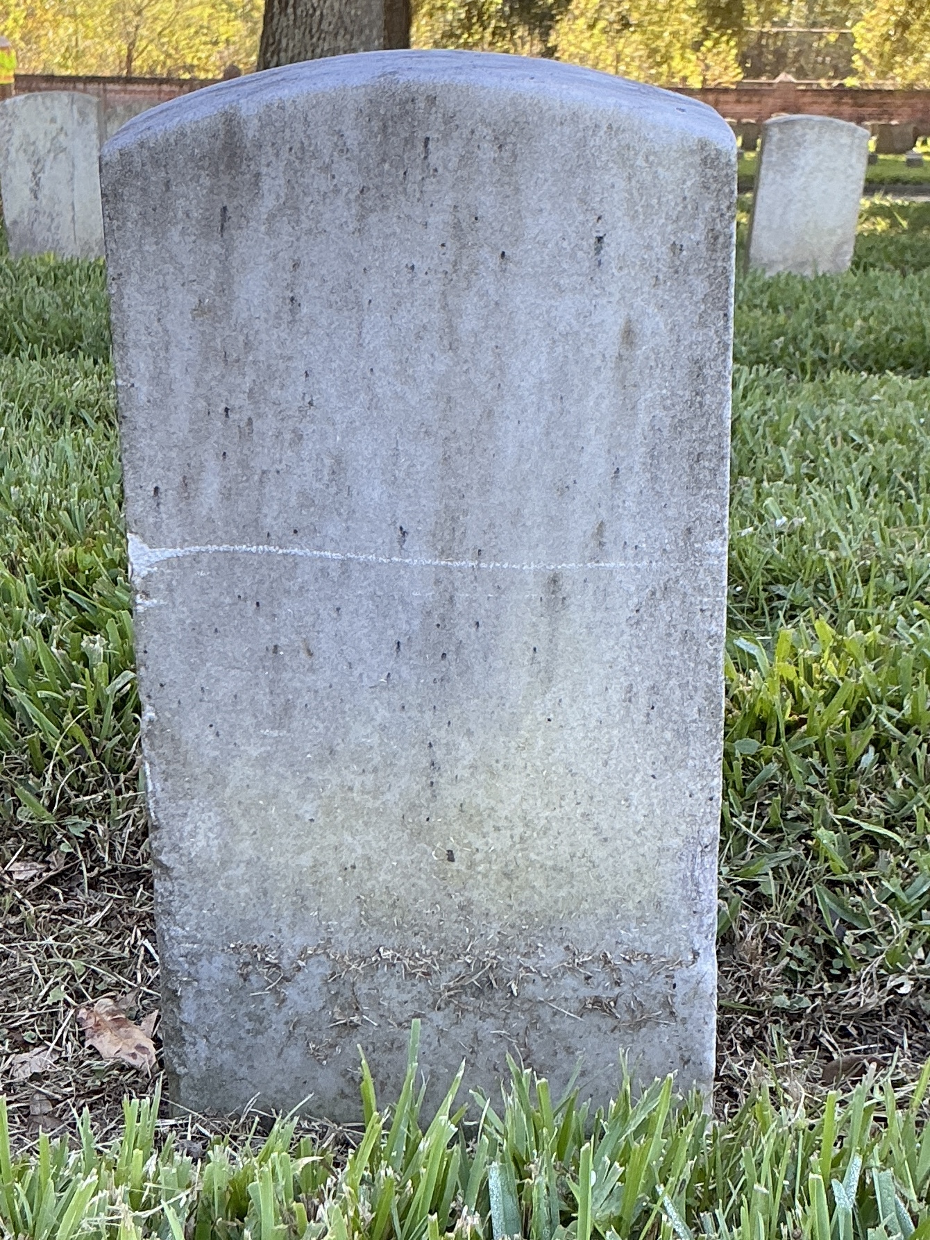 Back of historic upright marble headstone with recessed shield face.