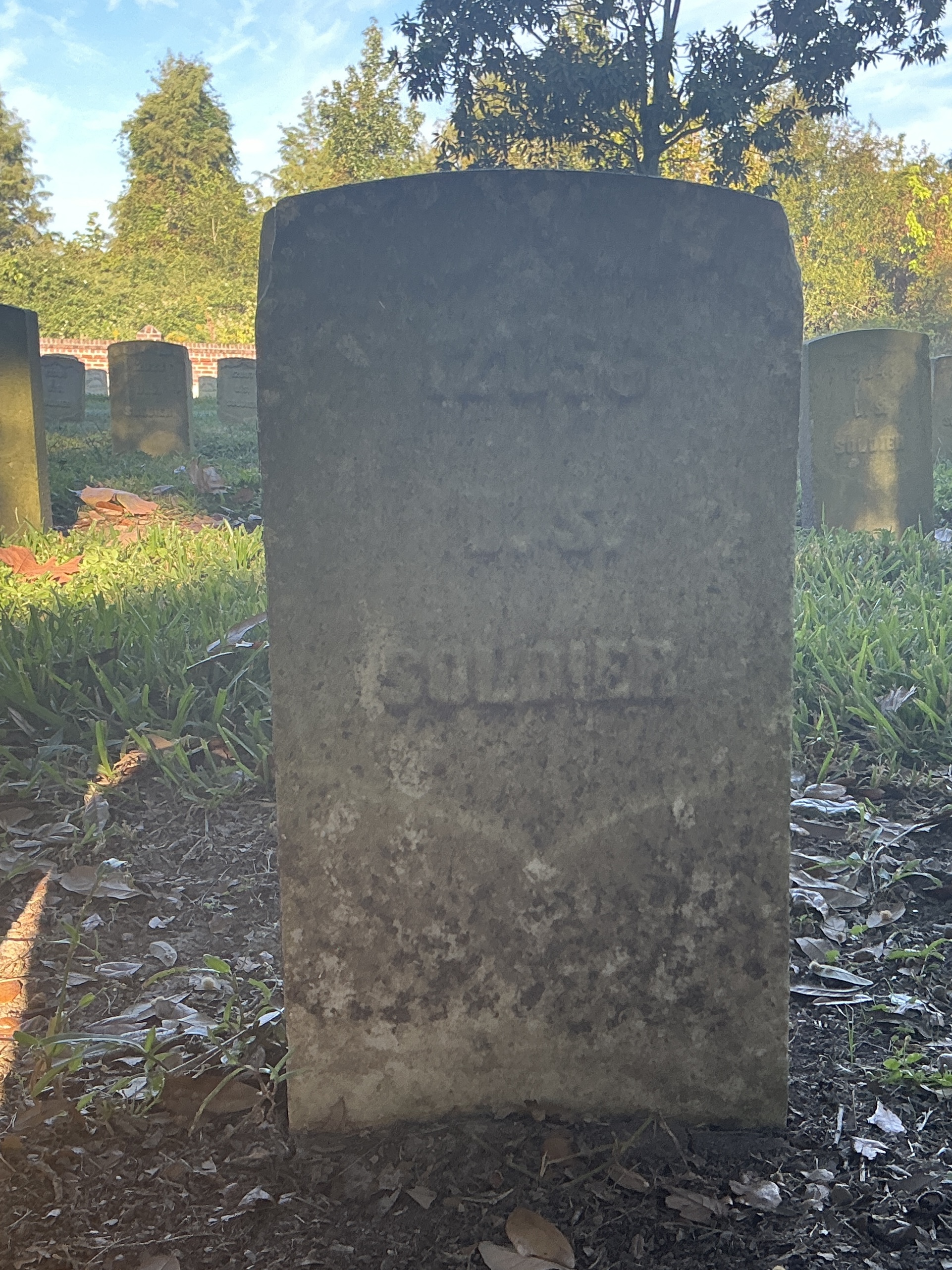 Front of historic upright marble headstone with recessed shield face.