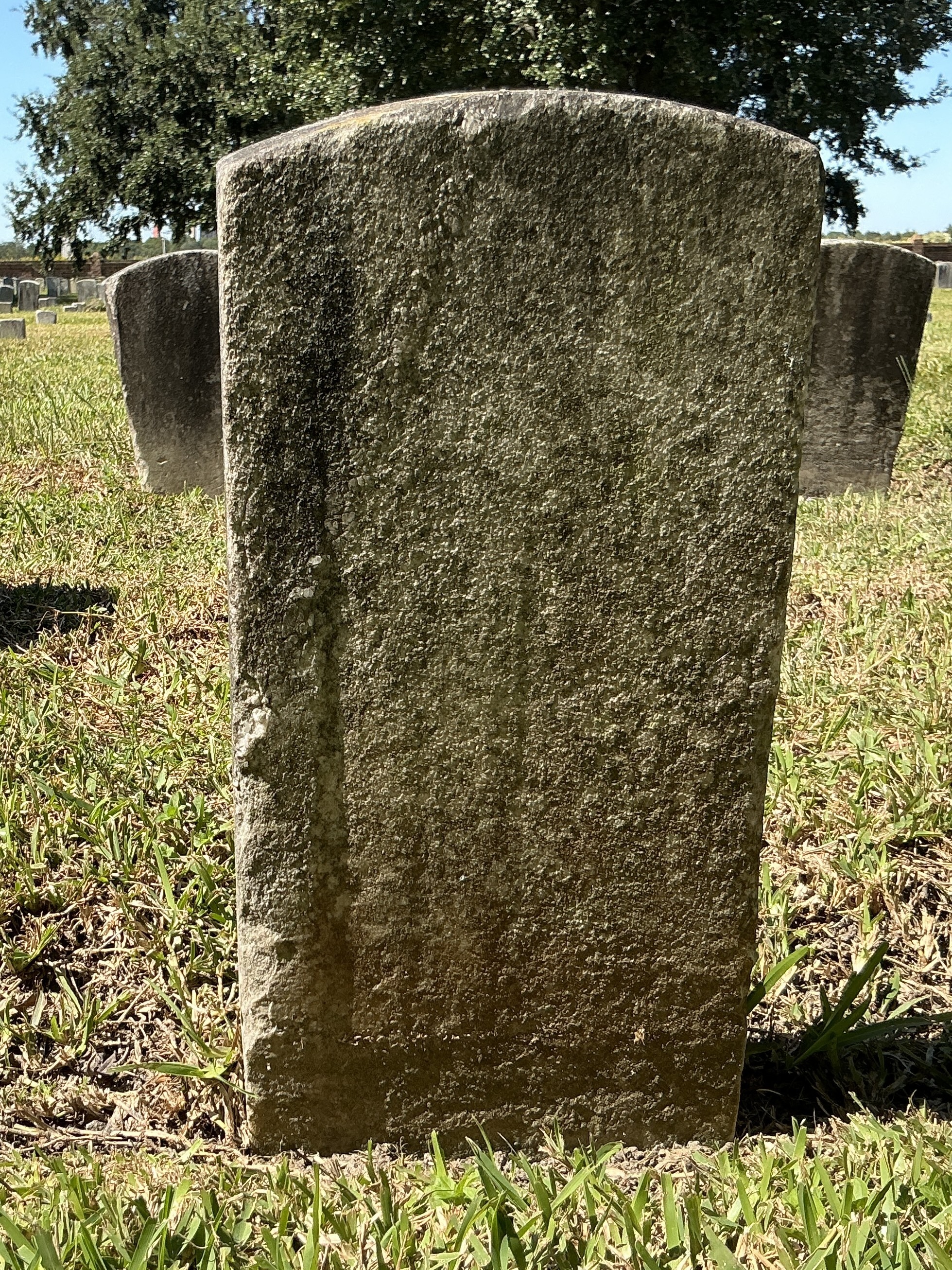 Back of historic upright marble headstone with recessed shield with recessed lettering face.