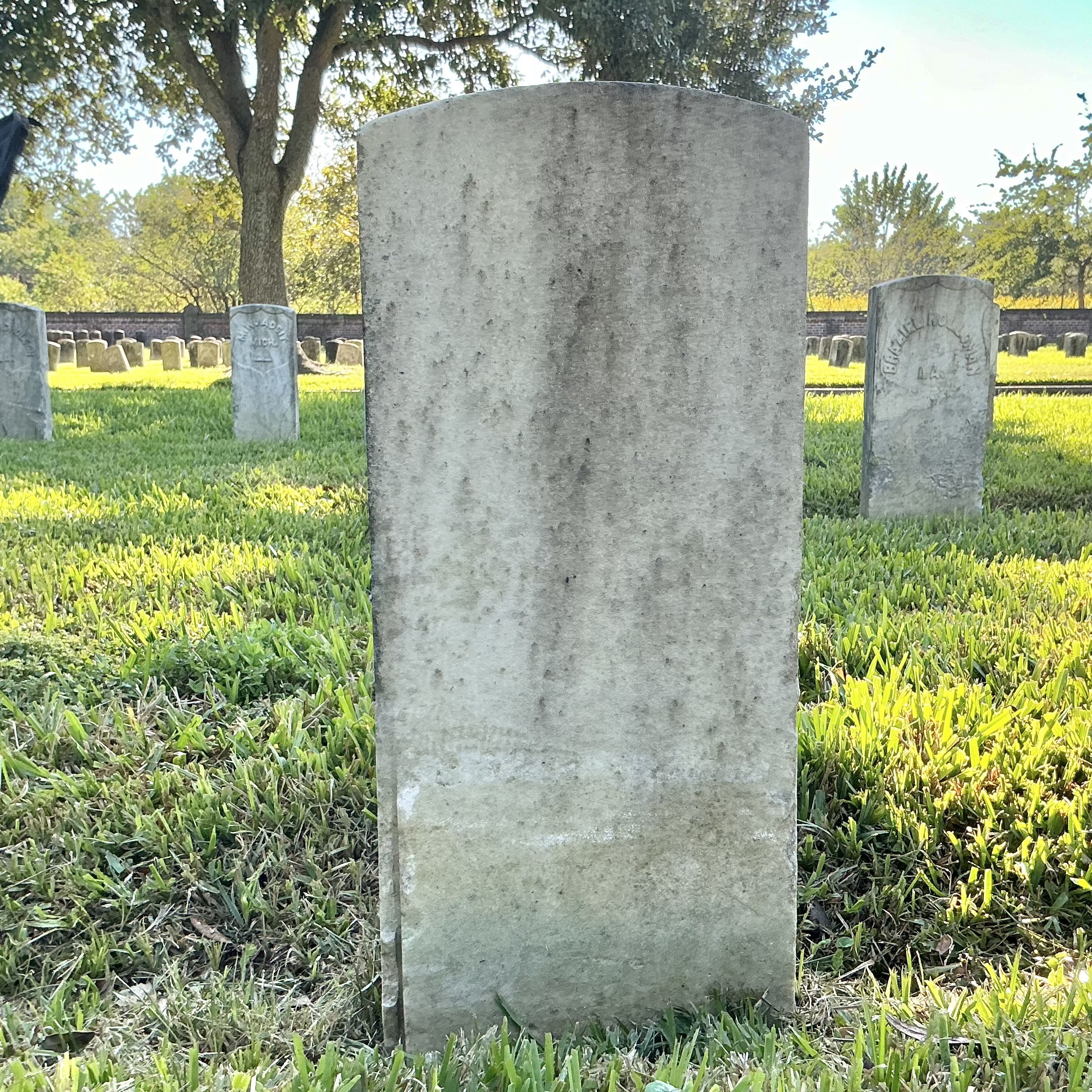 Back of historic upright marble headstone with recessed shield face.