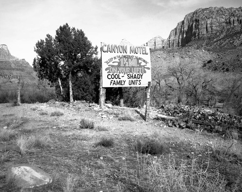 Roadside signs in Springdale. Canyon Motel 'Sleep in the shadow of the Watchman. 1-1/2 mi on your left. Cool shady family units'.