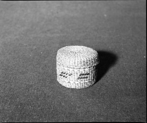 Marie Rozier Collection, Catalog No. 157. Object: Tshimshiam cover basket. Dimensions: 3 x 2-3/8". Materials: Red cedar bark, maidenhair fern stem, grass. Technology: Down to right slant of turns. Collection History: From Alaska Native Arts & Crafts. Bought by Mary Baker ca. 1970. Photographed by Michael Dixon, December 1982. Catalogued by Craig Bates and Barbara Beroza. Yosemite Collections, National Park Service.