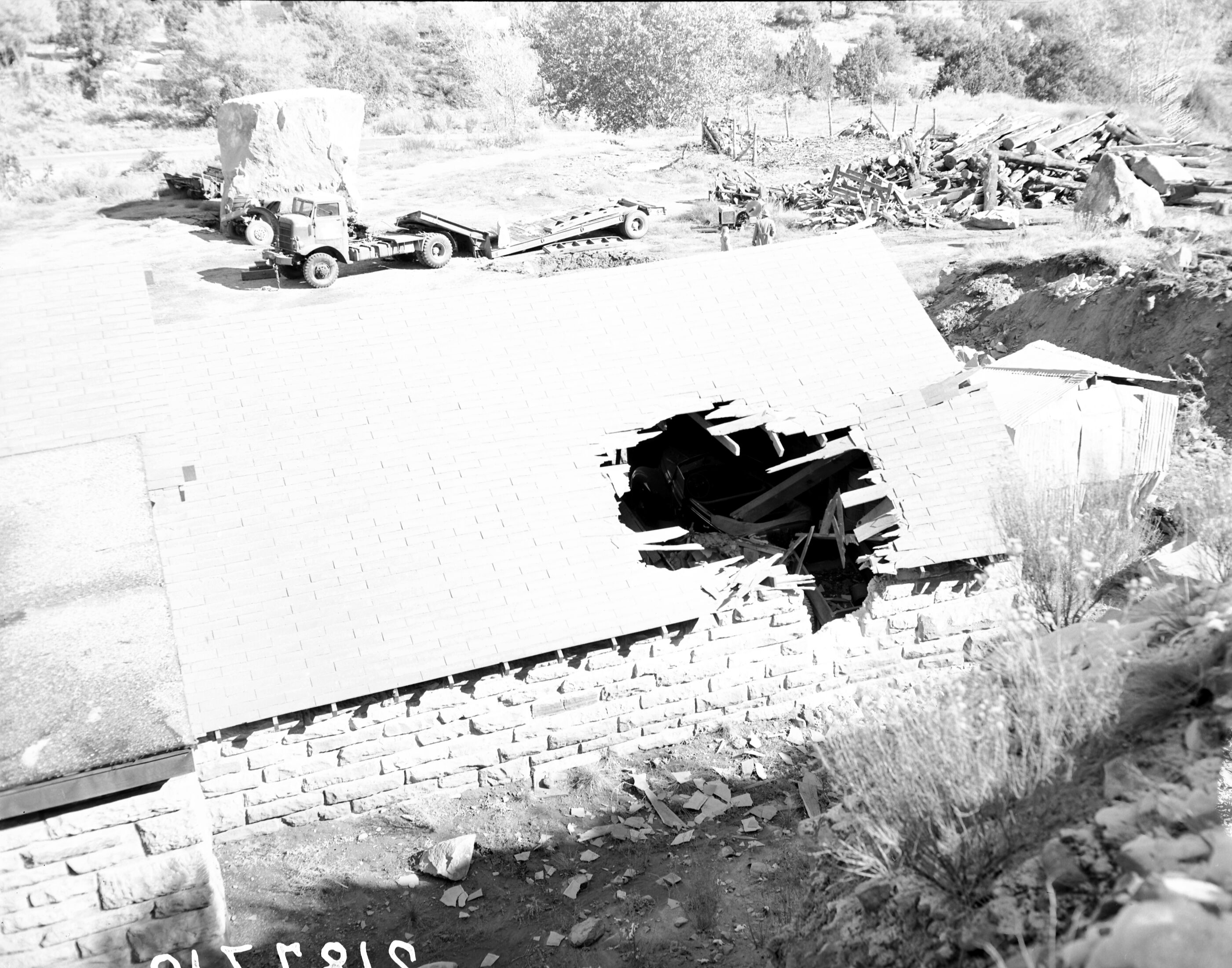 The rock slide of November 23, 1947, utility yard (Oak Creek maintenance area), large boulder on crushed truck. Woman and three children looking at the damage.
