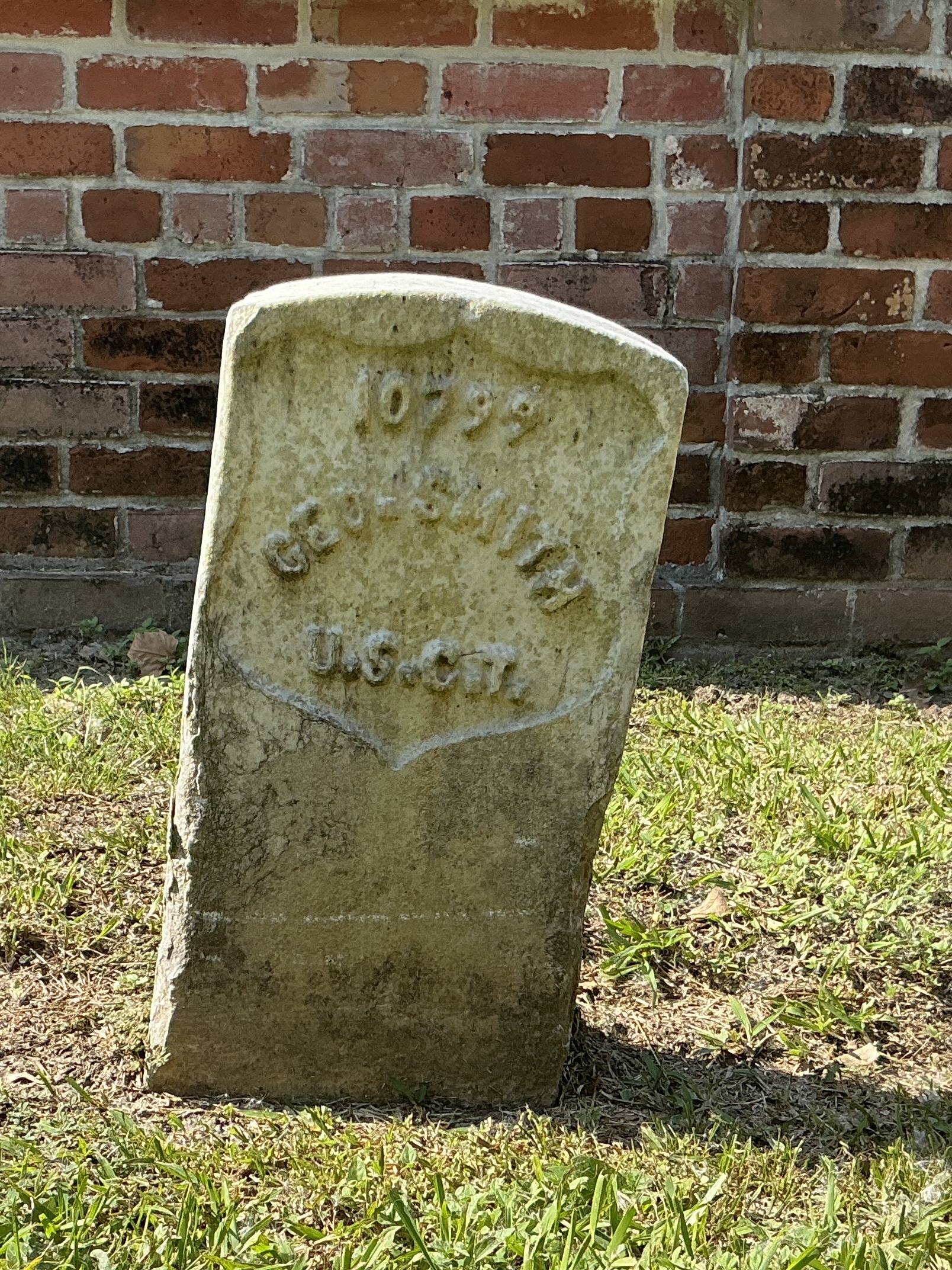 Front of historic upright marble headstone with recessed shield face.