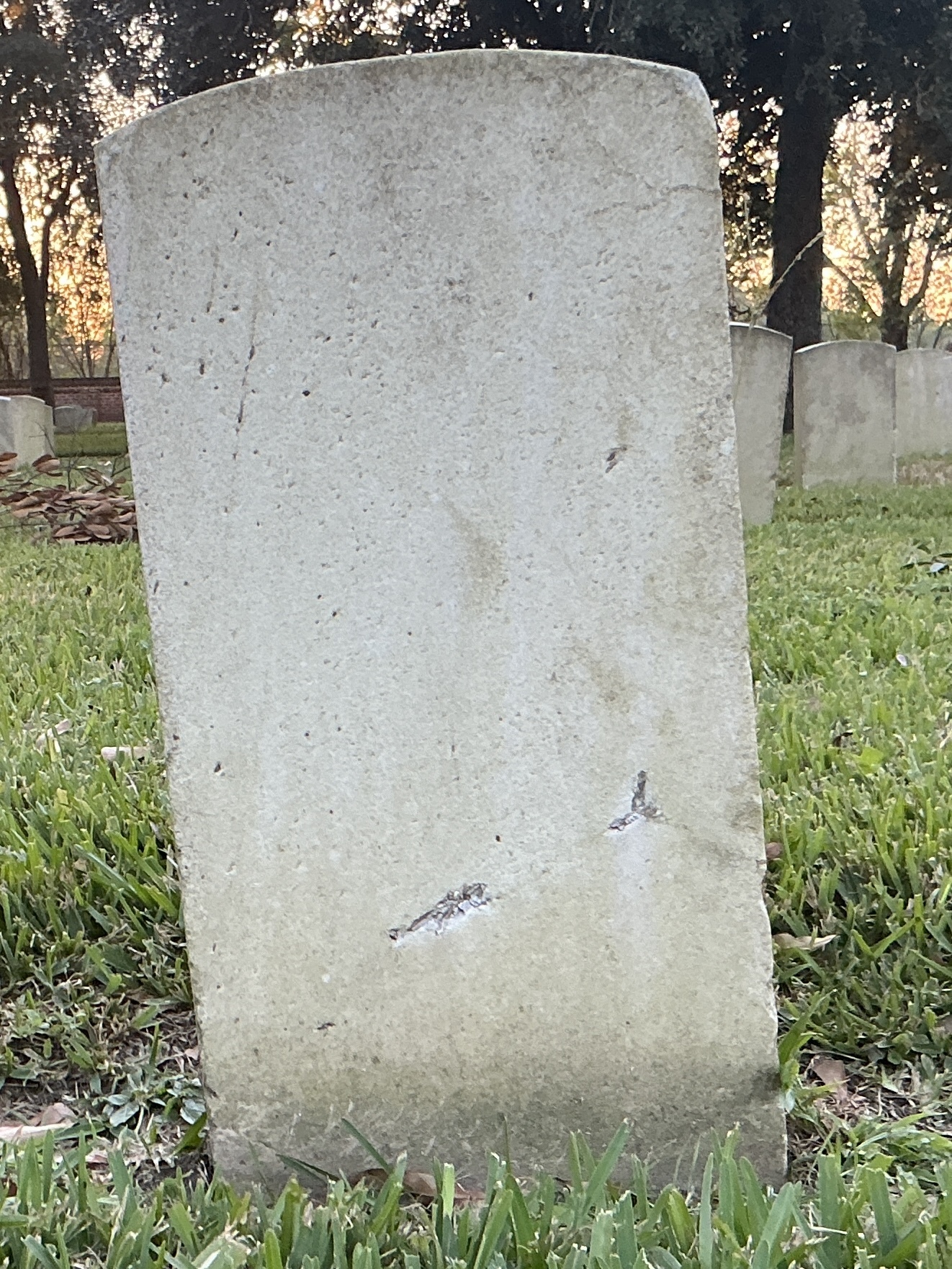 Back of historic upright marble headstone with recessed shield face.